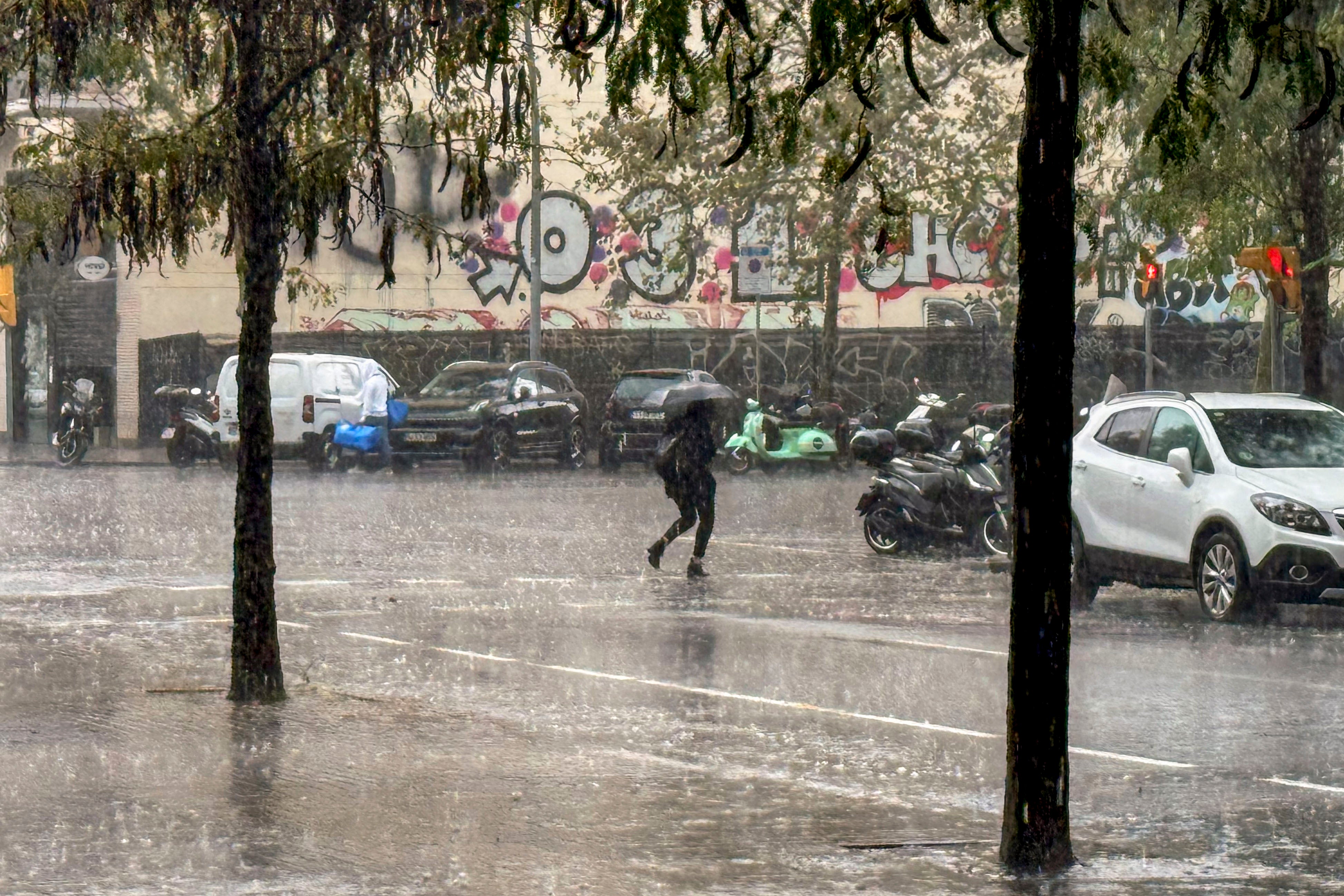 Osoba koja prelazi ulicu u kišnoj Barceloni tijekom drugog udarca lošeg vremena u ožujku