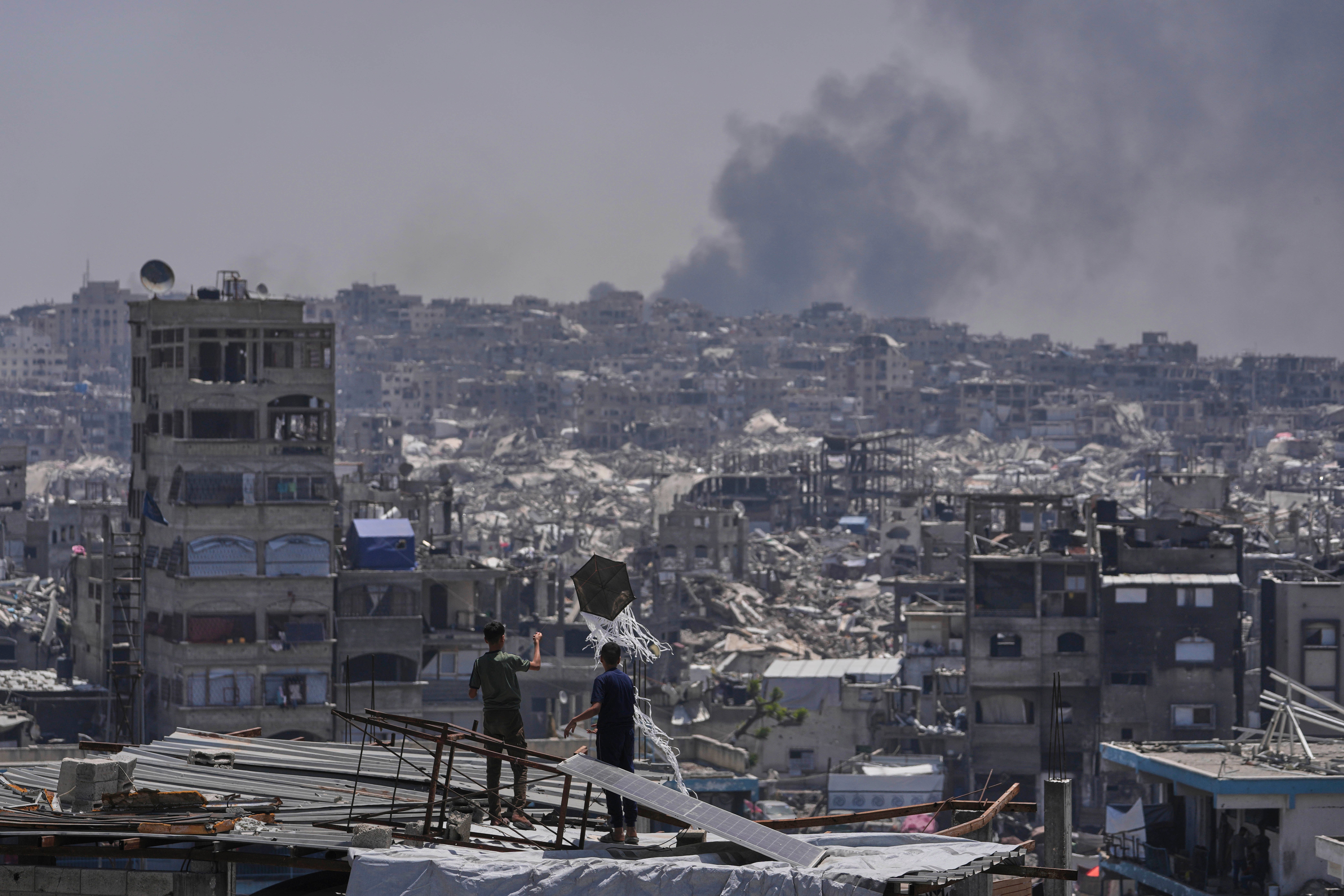 Palestinci gledaju kako se dim uzdiže nakon izraelskog zračnog udara u blizini Jabalia, u petak u Strip -u Gaze Strip