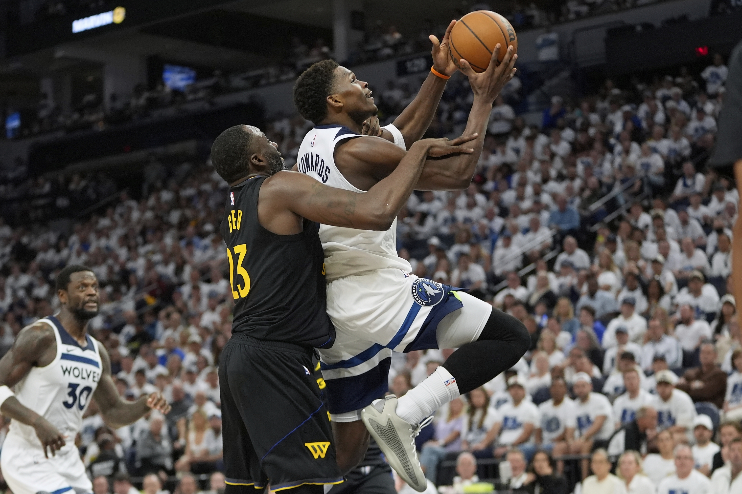 Minnesota Timberwolves čuvar Anthonyja Edwardsa (5), desno, nagazio je napadač Golden State Warriorsa Draymond Green (23) tijekom drugog poluvremena igre 1 iz NBA košarke u drugom krugu doigravanja, u utorak, 6. svibnja, 2025., u Minneapolisu. (AP Photo/Abbie Parr)