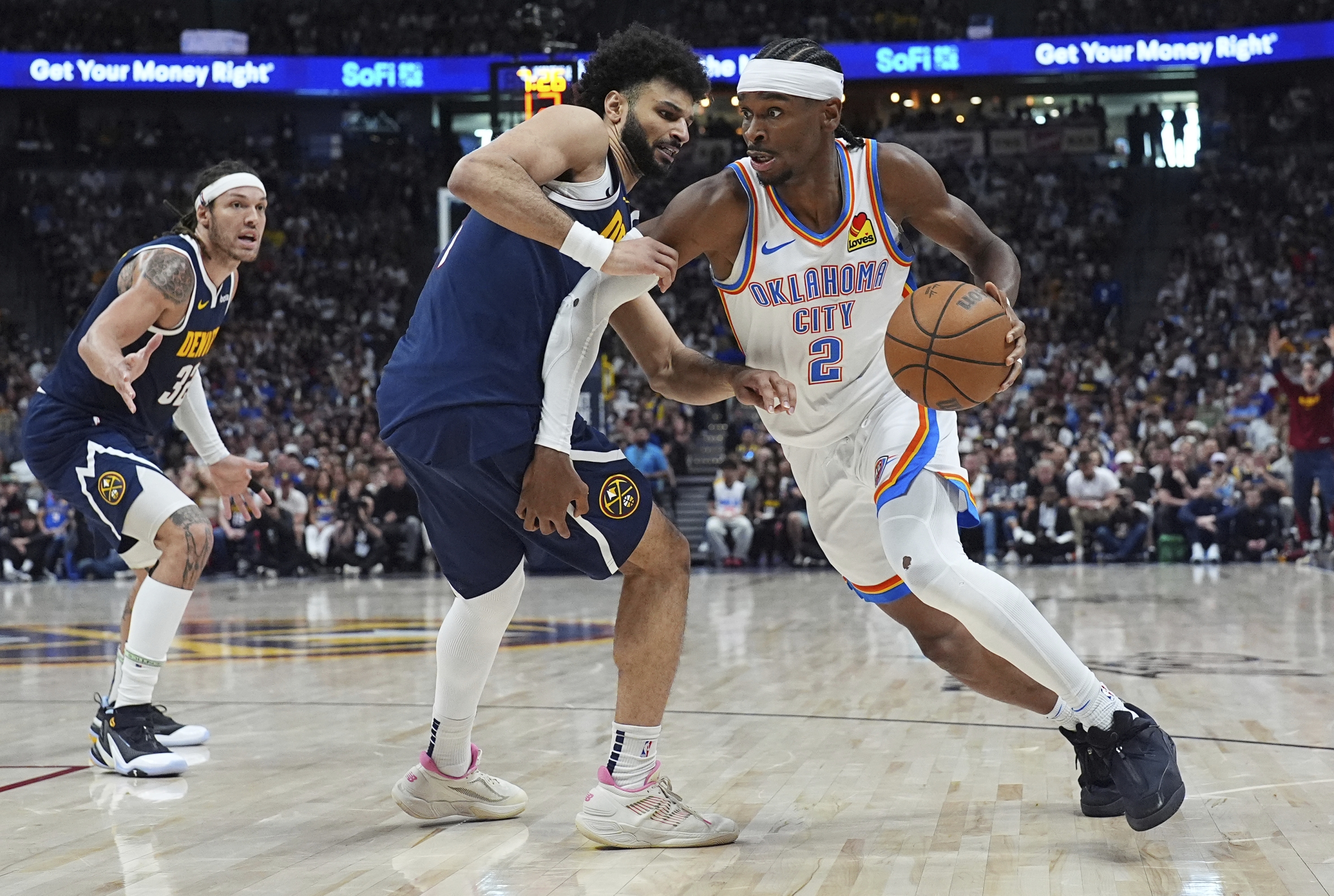 Oklahoma City Thunder Guard Shai Gilgeous-Alexander, desno, vozi se pokraj Denver Nuggetsa čuvara Jamala Murrayja, centra, i napadača Aarona Gordona u drugom poluvremenu igre 4 u polufinalu NBA košarkaške doigravanja u nedjelju, 2025., U Denveru. (AP Photo/David Zalubowski)