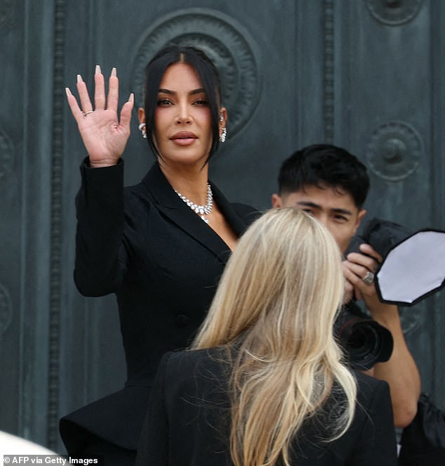 Kardashian - koja je bila odjevena u crno odijelo suknje i sunčane naočale - mahala je na promatračima