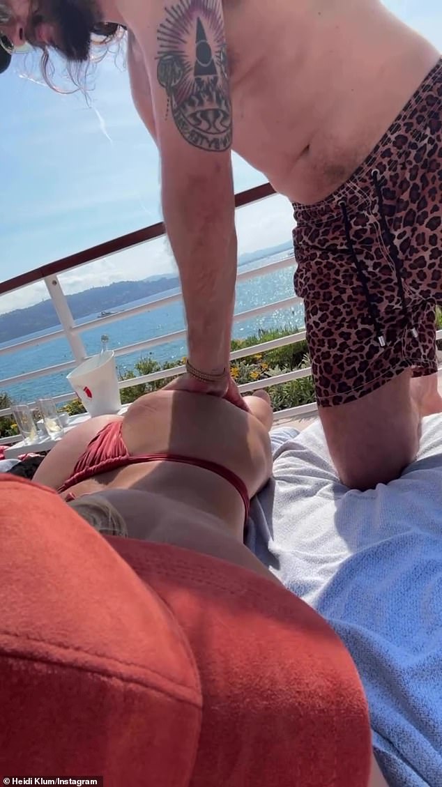 Njezin supružnik uzeo je vrijeme koristeći njegove jako tetovirane ruke kako bi trljao ulje po njenom derriereu dok se ona nasmiješila za kameru