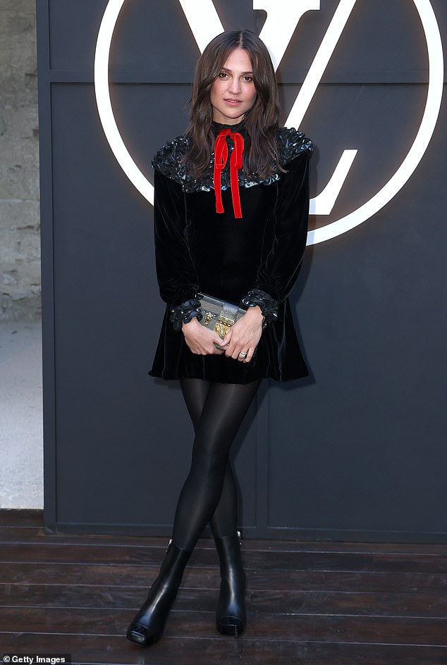 Alicia Vikander je zamolila sofisticiranost u crnoj baršunskoj mini haljini s crvenim lukom i ruffid manžetom