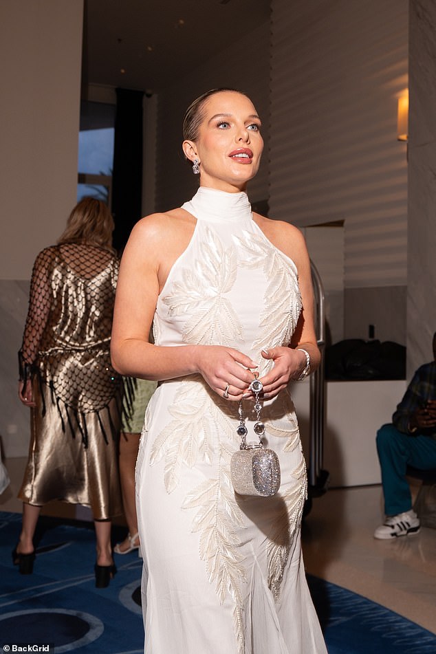 Glamurozni odjevni predmet izložio je tonirane ruke, ukrašen je s detaljima pera na bodici, a na stražnjoj strani je bio zališan vlak