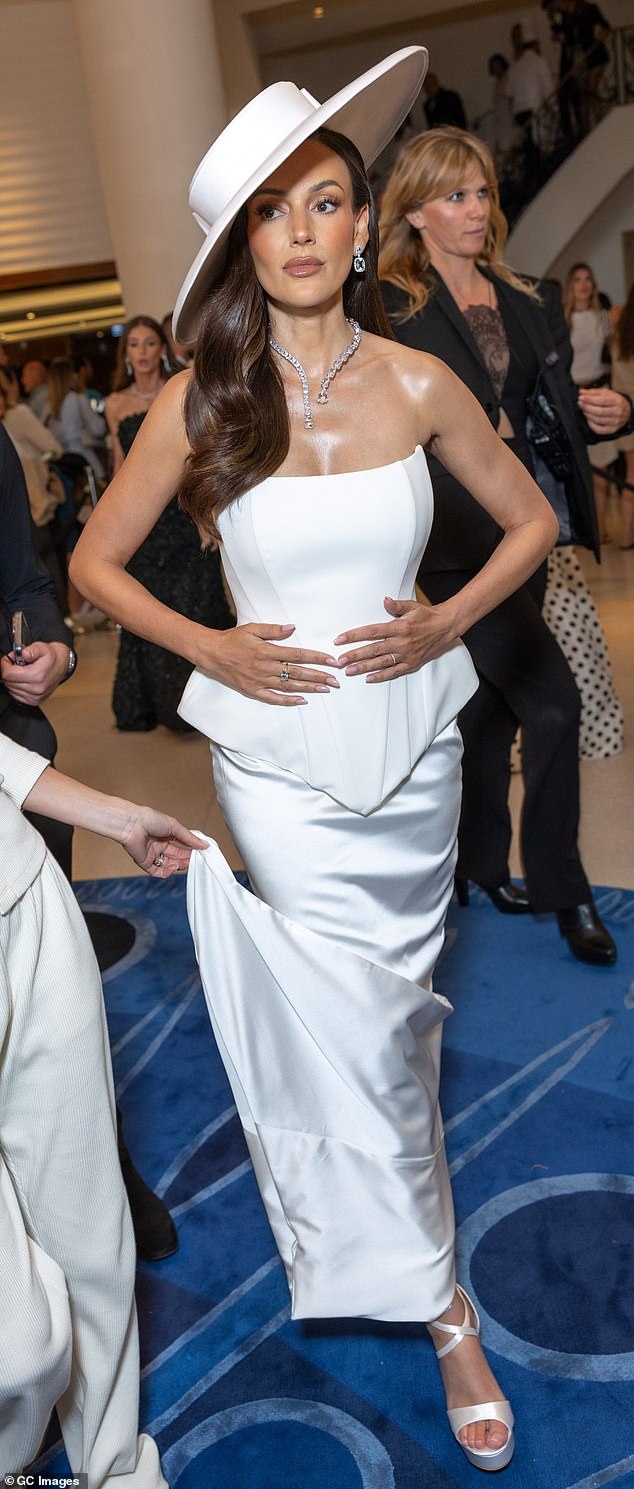 Michelle je okrenula glave dok je izlazila u zadivljujućoj bijeloj kaišenoj haljini bez naramenica, koja je sadržavala Peplum dizajn i suknju za zagrljaj lika