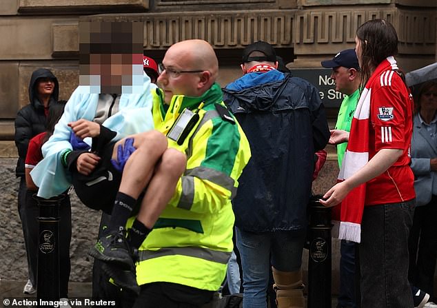 Emergency services rushed to the scene and 27 people, including four children, were taken to hospitals across the city. Pictured: A paramedic carries an injured fan out the crowd