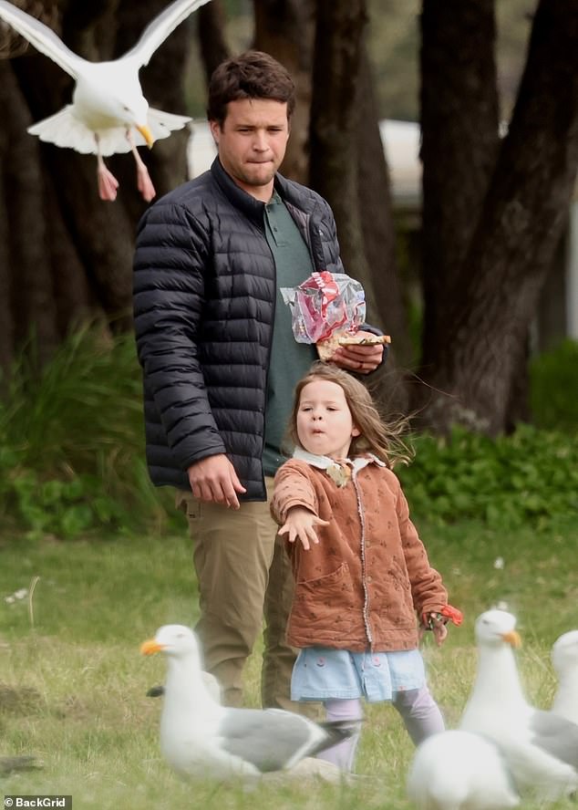 Chandler odjeven za udobnost u bež hlačama, tamnozeleni skakač i jaknu za puhanje za izlet