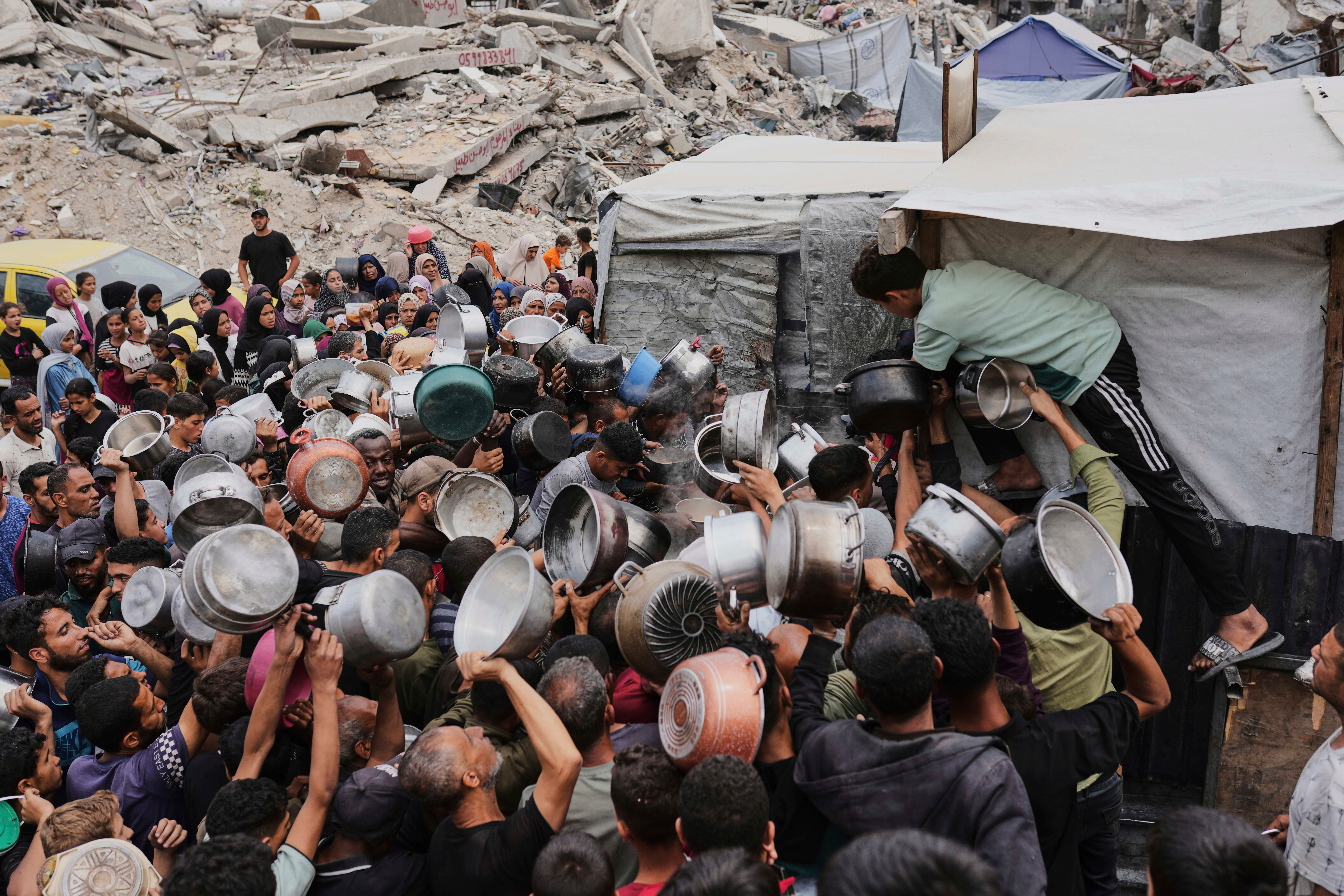 Palestinci se bore da dobiju doniranu hranu u kuhinji zajednice u Jabaliji, Strip u sjevernoj Gazi