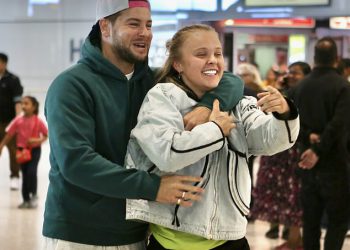 Chris Hughes slatko pozdravlja Jojo Siwa natrag u Veliku Britaniju s gomilom crvenih ruža dok par napušta Heathrow ruku u ruku nakon što je potvrdio romantiku