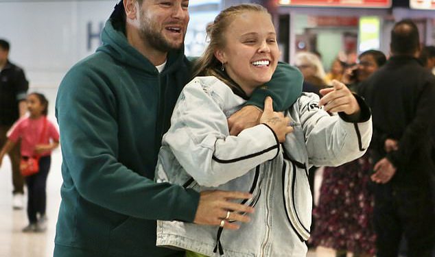 Chris Hughes slatko pozdravlja Jojo Siwa natrag u Veliku Britaniju s gomilom crvenih ruža dok par napušta Heathrow ruku u ruku nakon što je potvrdio romantiku