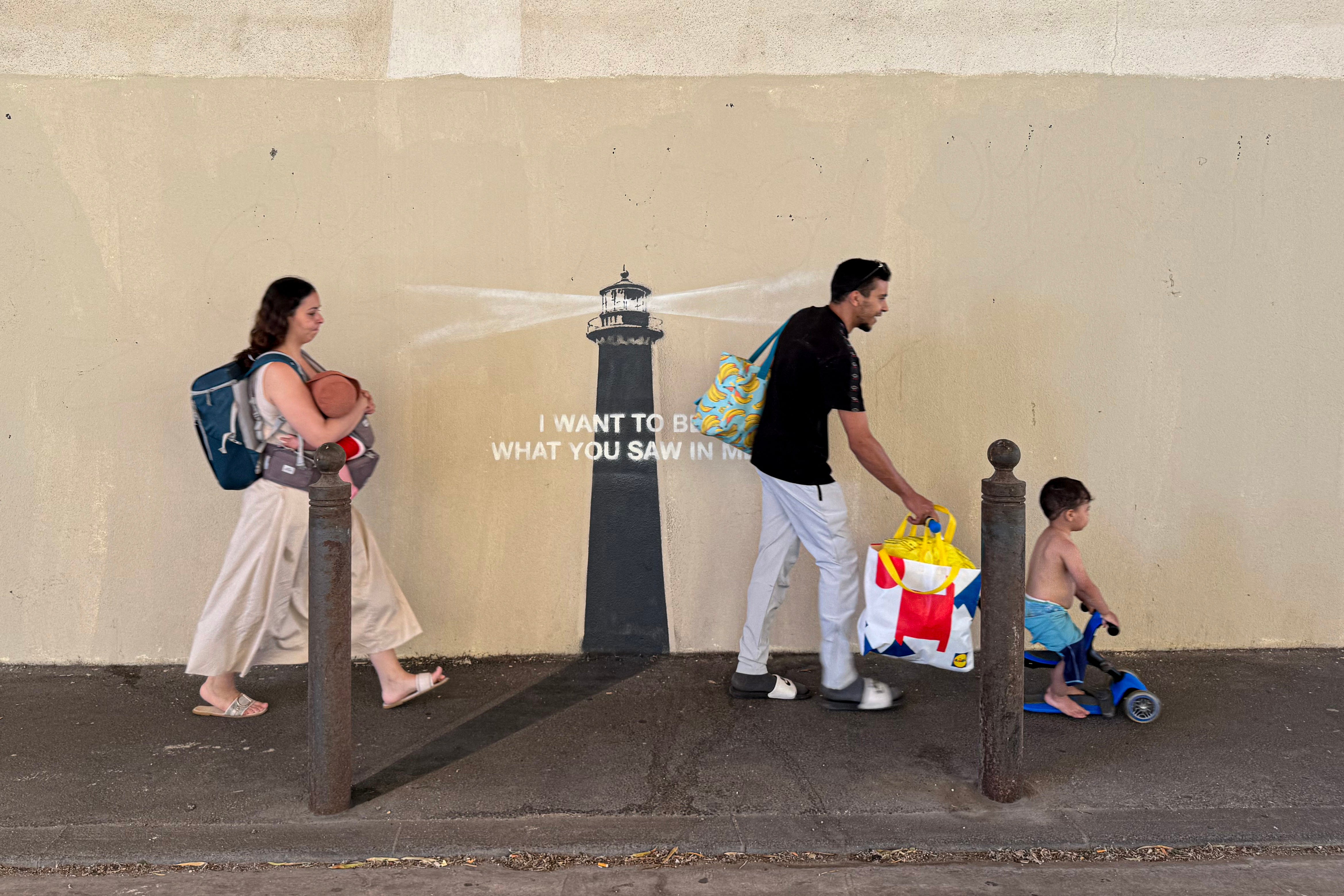 Pješaci prolaze pored novoobjavljenih umjetničkih djela uličnog umjetnika Banksyja na fasadi zgrade u Marseilleu