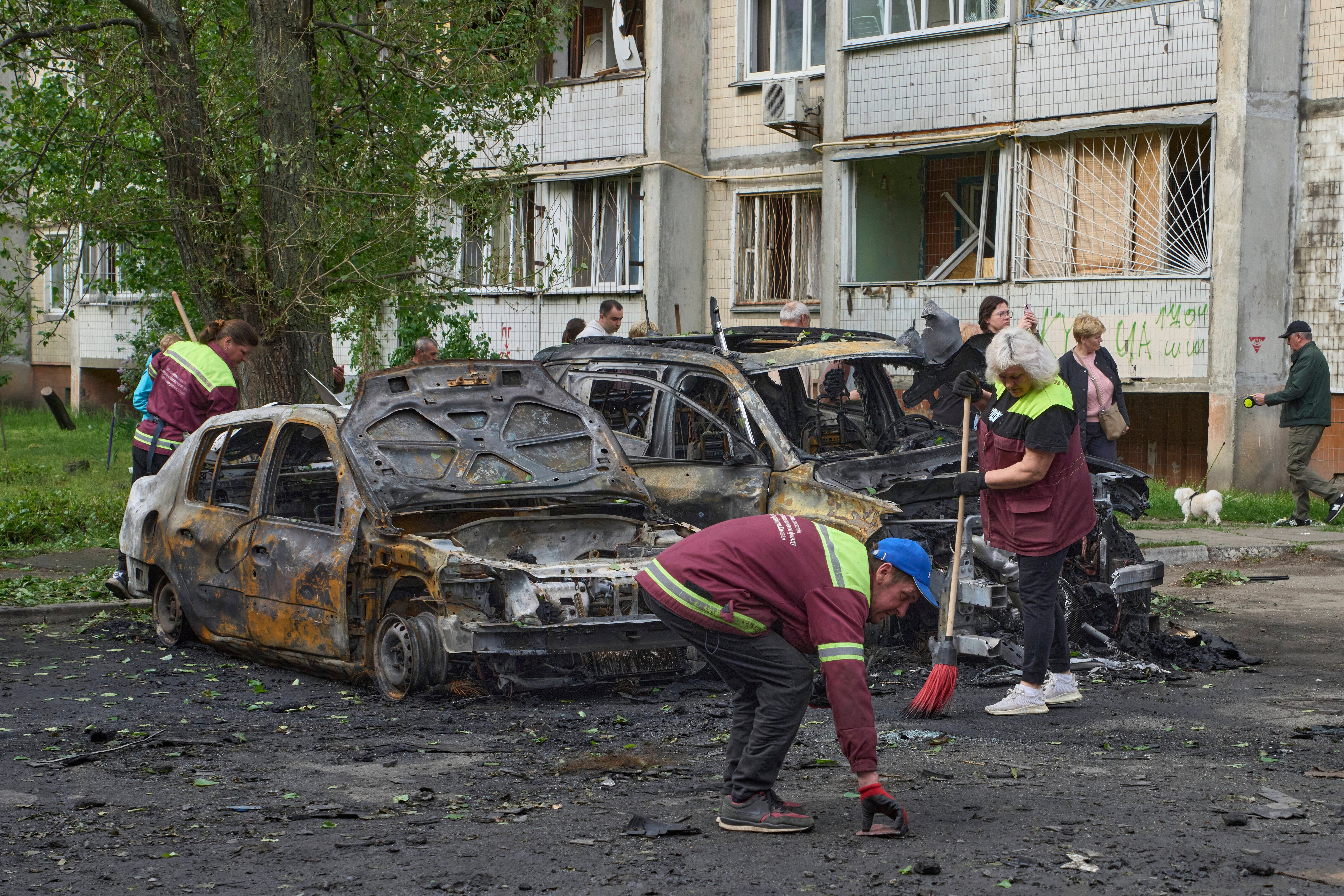 Općinski radnici čiste oko izgorjelih automobila u stambenom području nakon ruskog napada bespilotnih letjelica u Kiyivu, Ukrajina, nedjelja, 4. svibnja 2025. (AP Photo/Efrem Lukatsky)