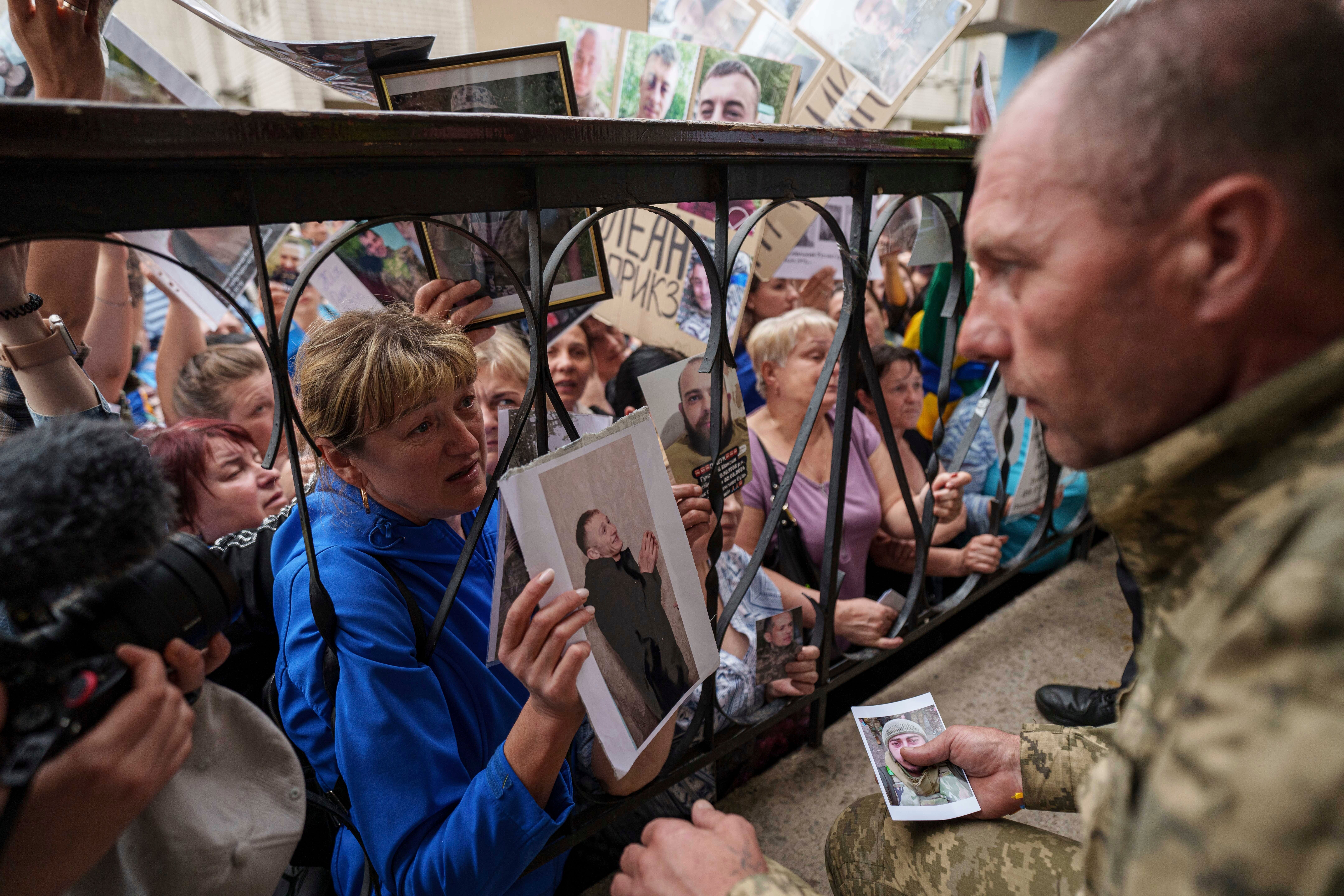 Ljudi prikazuju fotografije svojih propuštenih rođaka ukrajinskim vojnicima tijekom razmjene ratnih zarobljenika između Rusije i Ukrajine, u regiji Chernyhiv, Ukrajina, u subotu, 24. svibnja 2025. (AP Photo/Evgeniy Maloletka)