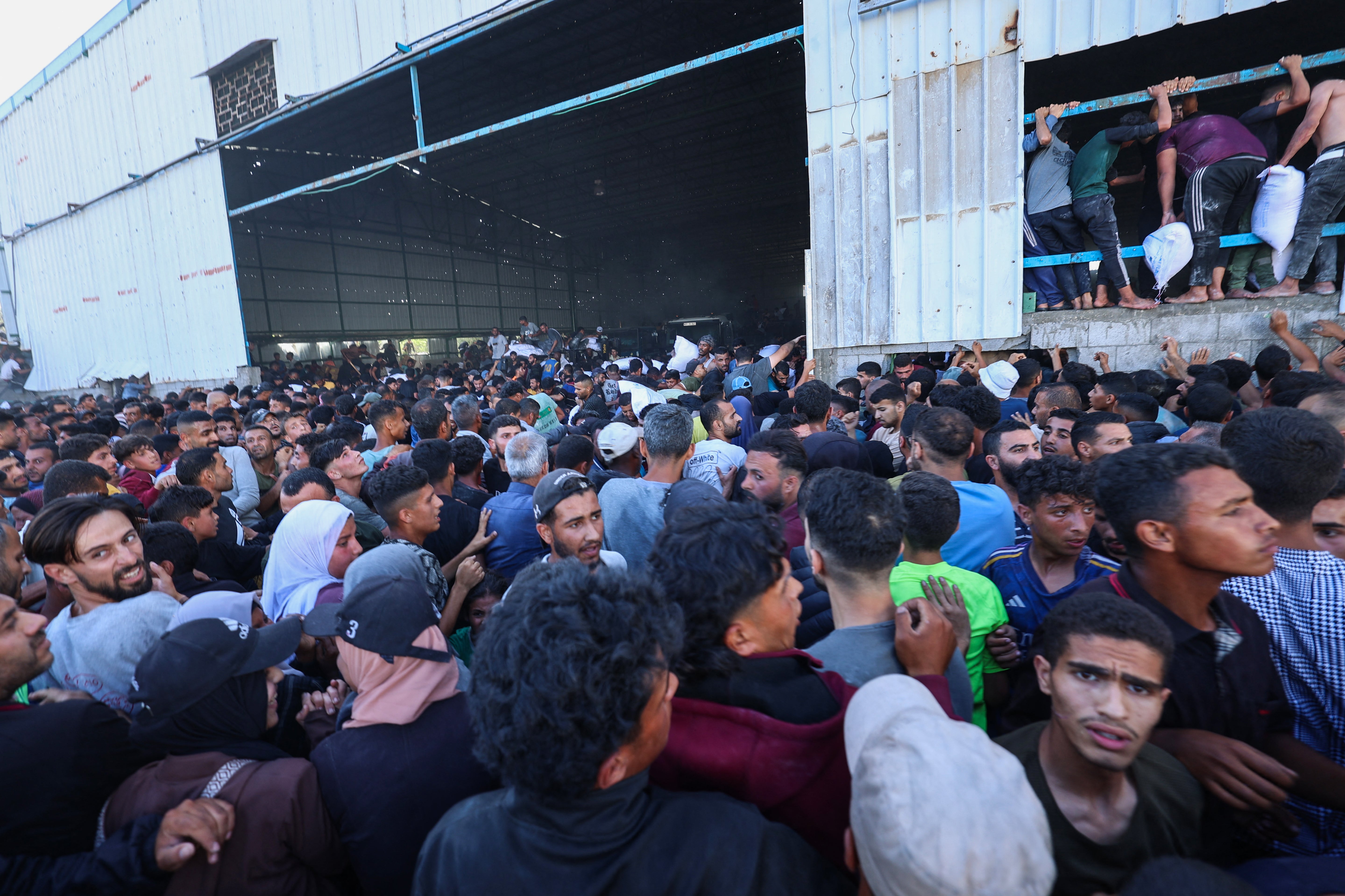Raseljeni Palestinci trajektne vrećice za pomoć u hrani dok oluju Svjetsko skladište programa hrane u Deir El-Balah u središnjoj Gazi Strip