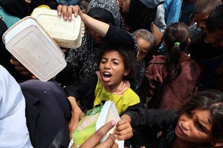 Palestinska djevojka reagira dok se ljudi okupljaju za topli obrok na točki distribucije hrane