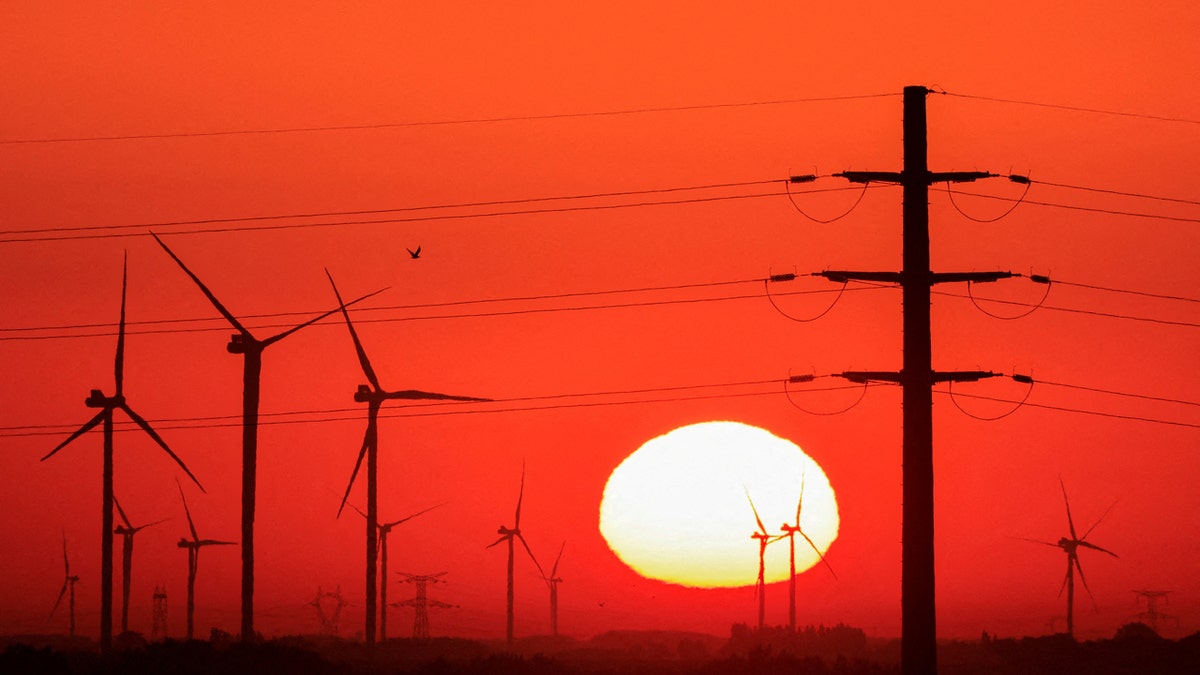 Turbine vjetrenjača i stupovi za proizvodnju električne energije prikazani su tijekom izlaska sunca u vjetroelektrani u Avesnes-le-sec, Francuska, 8. rujna 2023. godine.