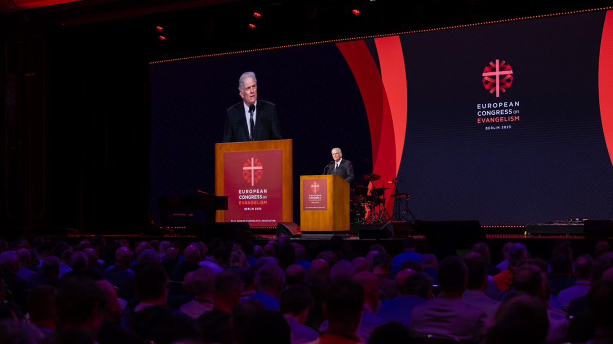 Franklin Graham govori na postolju tijekom Europskog kongresa o evangelizaciji u Berlinu, a njegova slika projicirana na velikom ekranu iza njega
