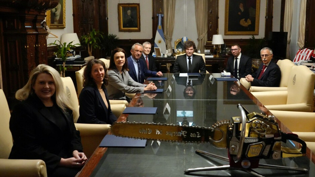 Kennedy i Milei sjede sa službenicima oko konferencijskog stola unutar Casa Rosada, sa zlatnom motornom pilom u prvom planu.