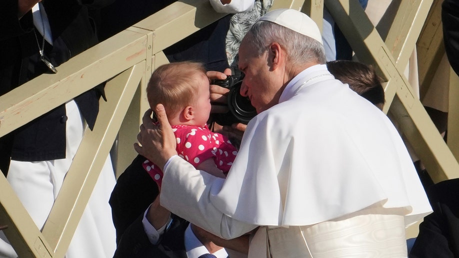 Papa Leo XIV drži dijete ispred svoje nastupne mase.