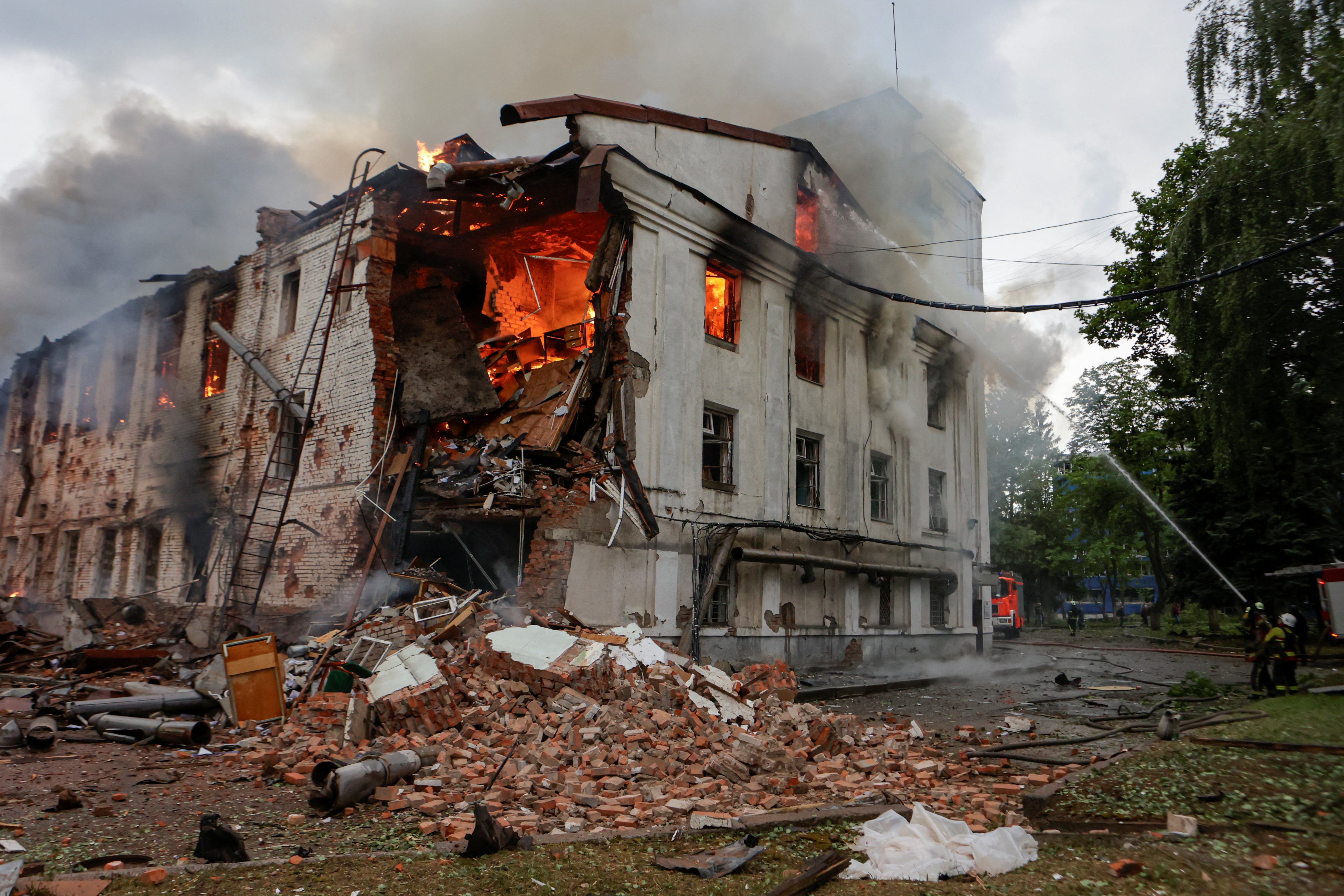 Vatrogasci rade na mjestu zgrade koju je pogodio ruski štrajk bespilotnih letjelica, usred napada Rusije na Ukrajinu, u Harkivu