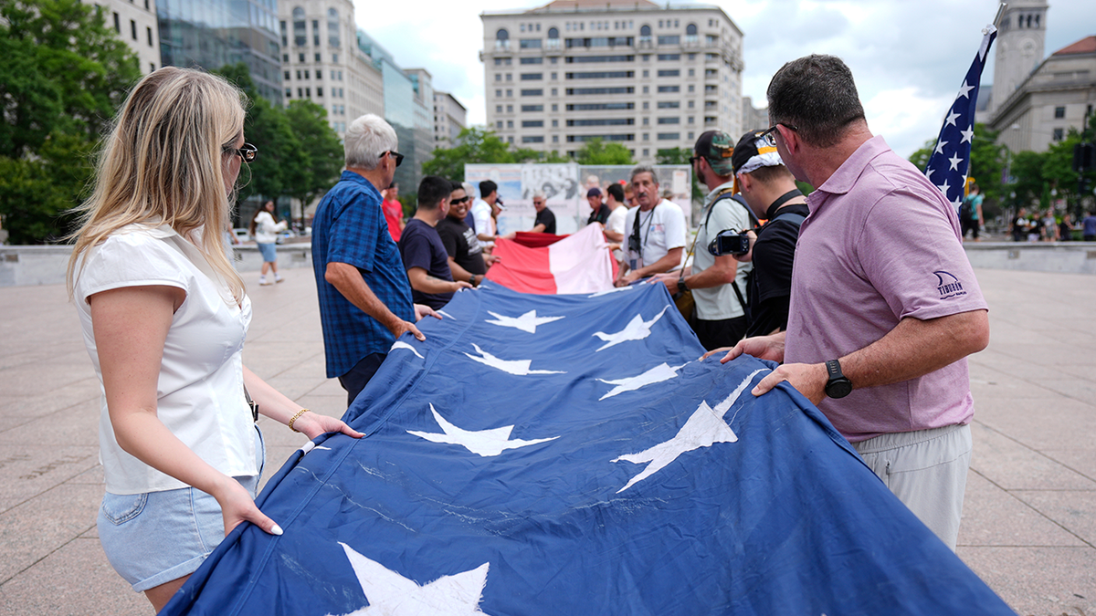 Ljudi savijaju veliku američku zastavu na Freedom Plaza prije parade koja je u subotu, 14. lipnja 2025., u Washingtonu, u Washingtonu.
