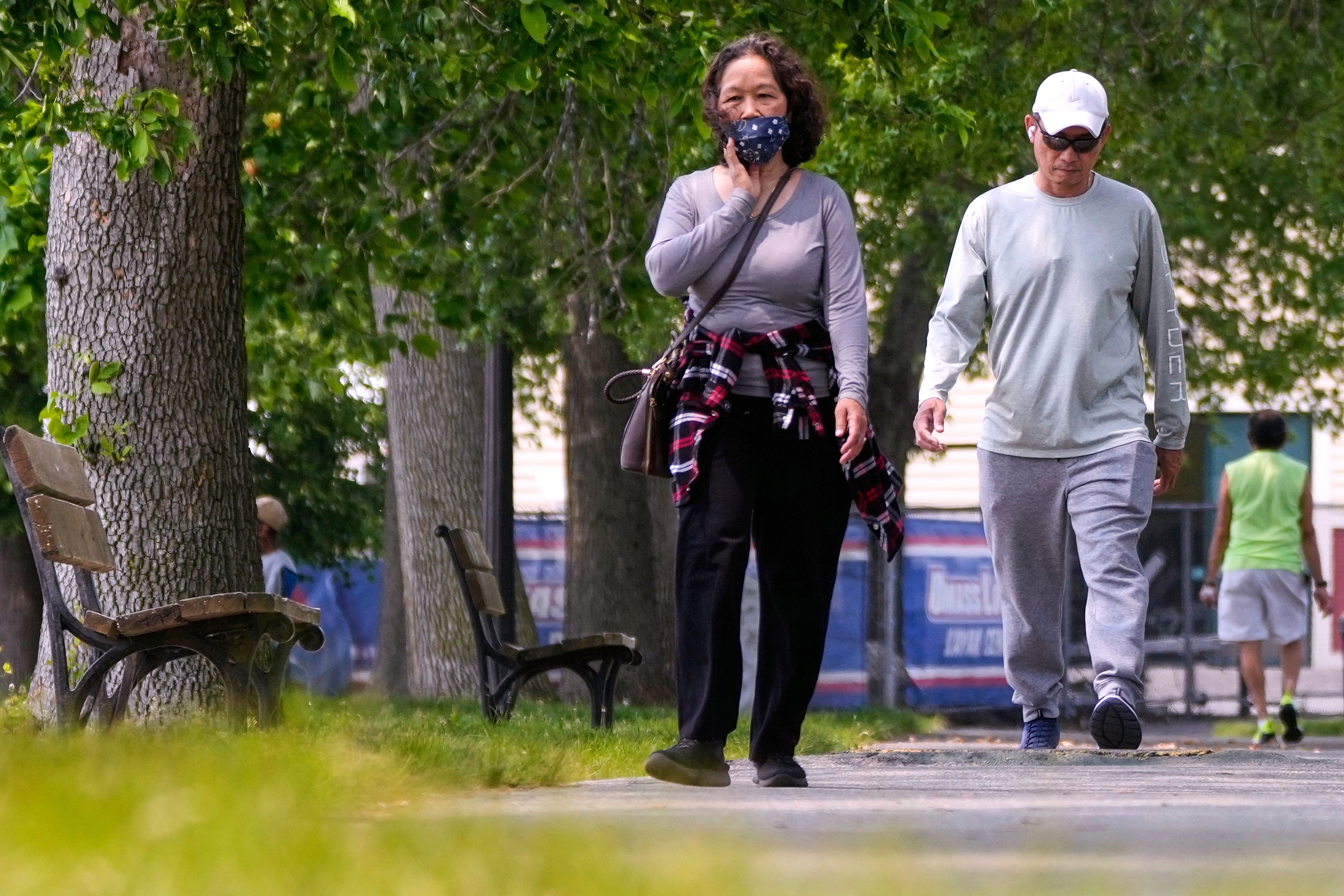 Žena nosi zaštitnu masku dok šeta obalama rijeke Merrimack, srijeda, 4. lipnja 2025., u Lowellu, Massanu