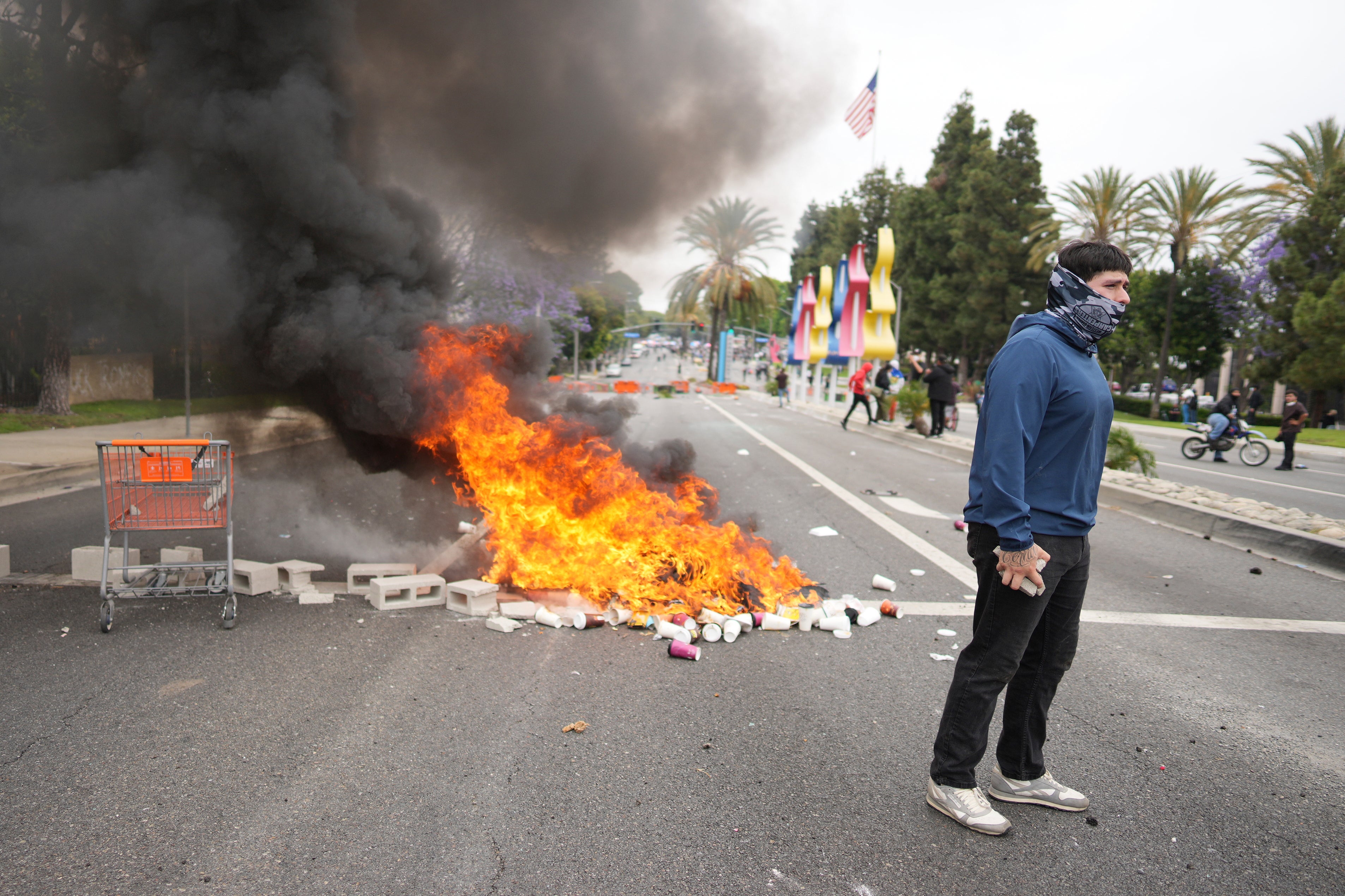Požar se gori kao prosvjednik suočava se s osobljem za provedbu zakona u pobuni i plinskim maskama tijekom demonstracije nad desecima ljudi pritvorenih u operaciji od strane ledenih agenata dan ranije u području Paramount u Los Angelesu