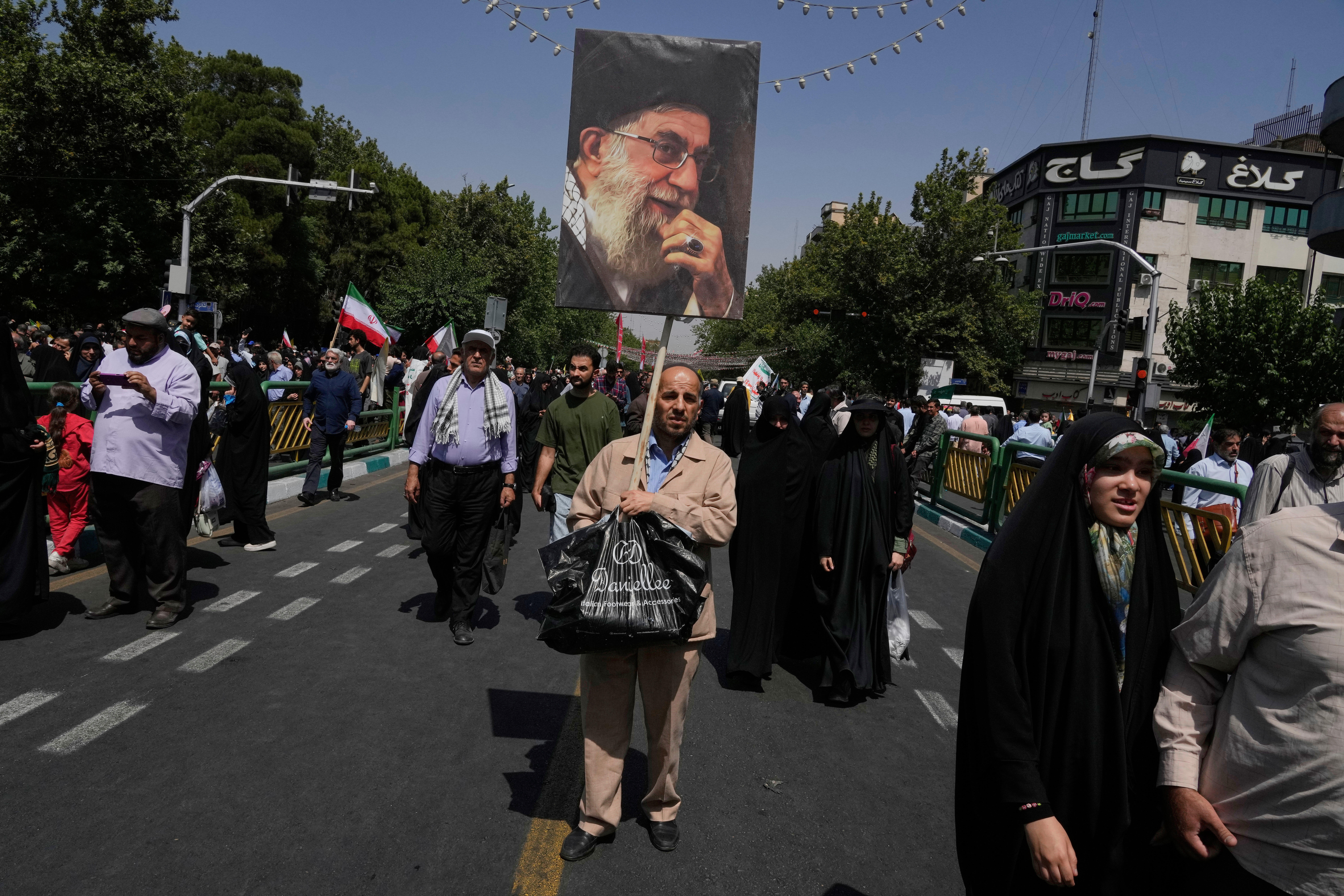 Prosvjednik nosi plakat iranskog vrhovnog vođu Ayatolaha Ali Khamenei tijekom prosvjeda zbog osude izraelskih napada na više gradova širom Irana, nakon ceremonije molitve u petak u Teheranu u Iranu, petak, 20. lipnja 2025. (AP Photo/Vahid Salemi)