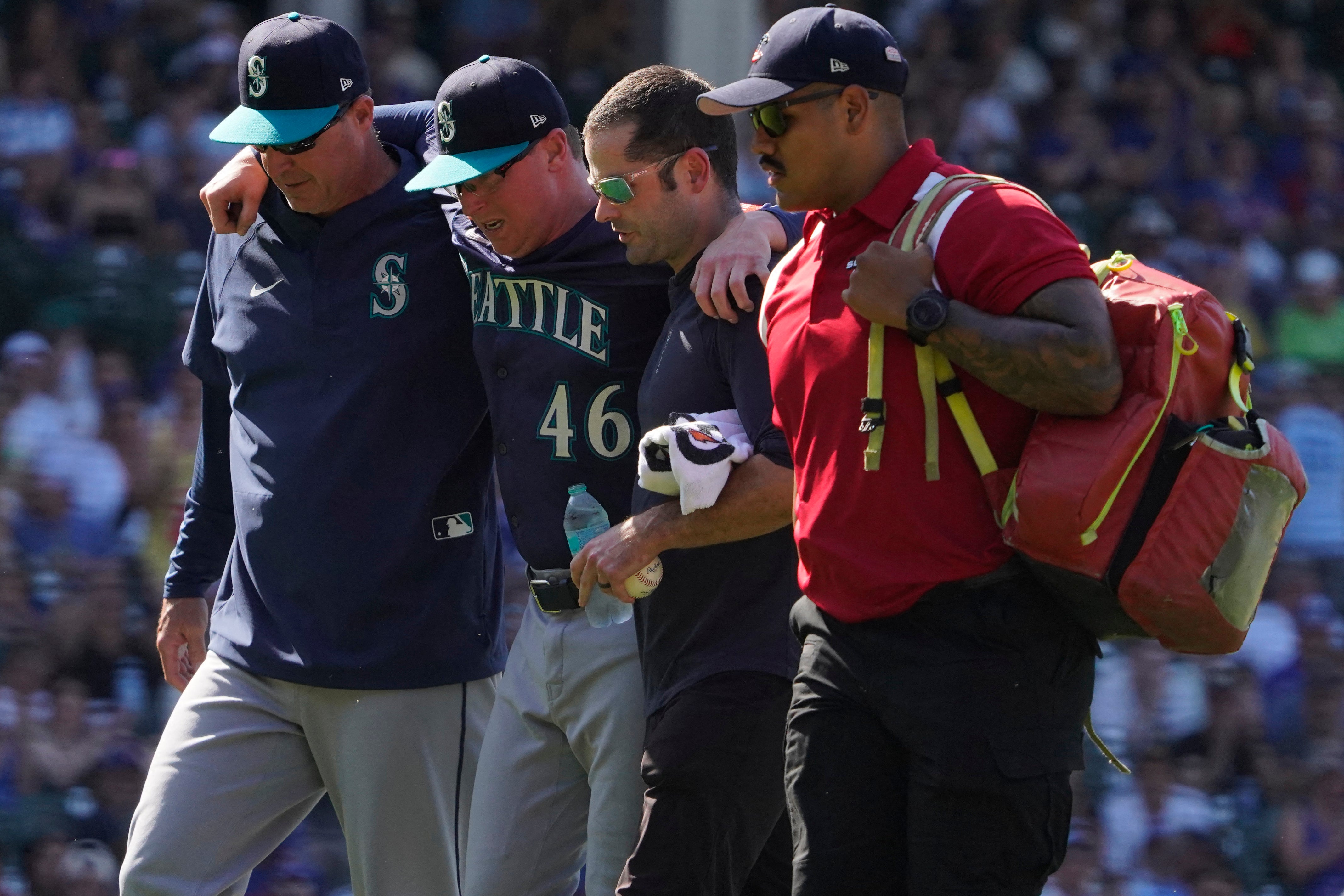 Backer Seattle Mariners Trent Thornton pomaže se na terenu nakon što je dobio toplinski udar tijekom osmog inninga protiv Chicago Cubsa na Wrigley Field