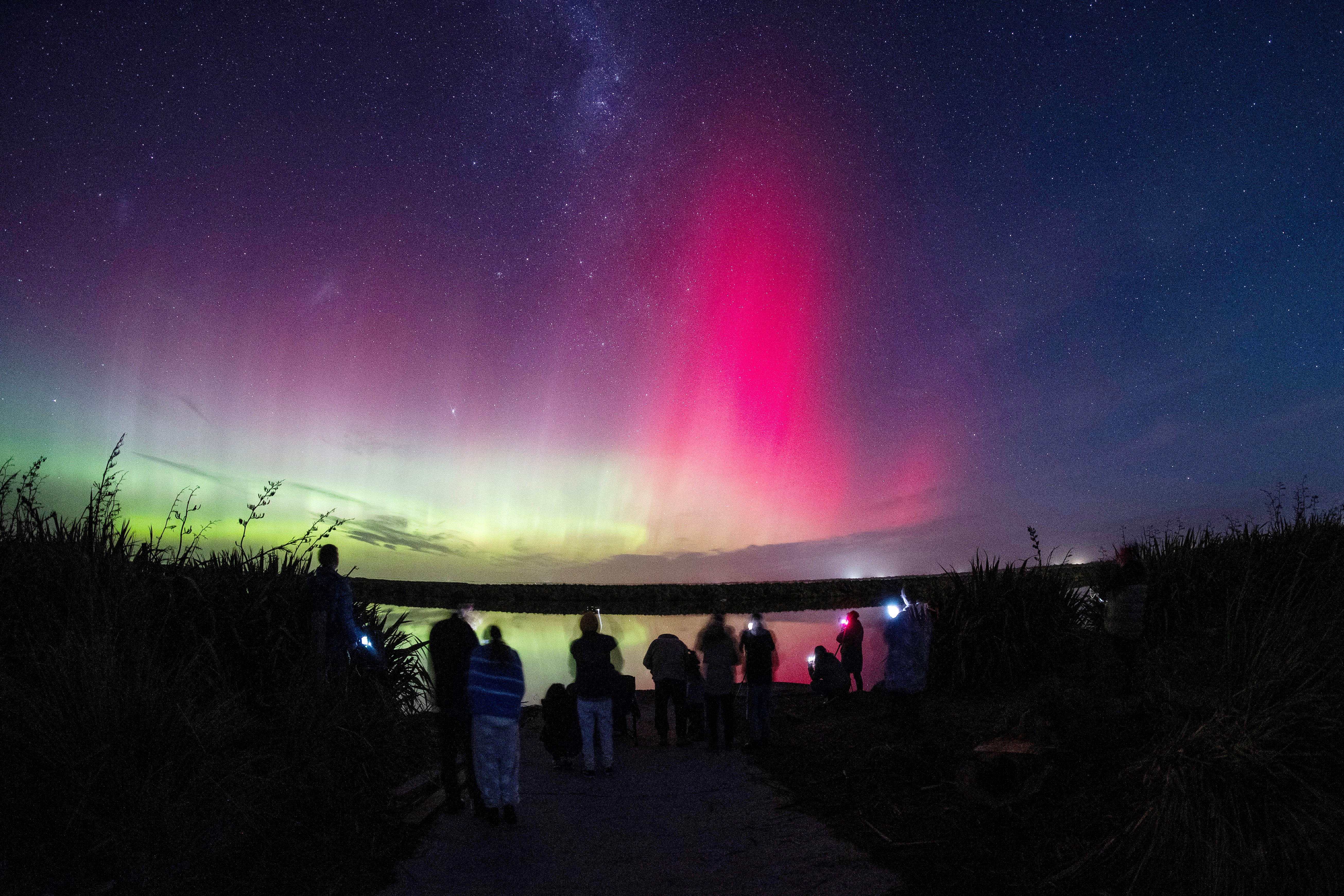 Ljudi gledaju Aurora Australis, poznatu i kao Južna svjetla, svijetli na horizontu preko jezera Ellesmere na periferiji Christchurcha