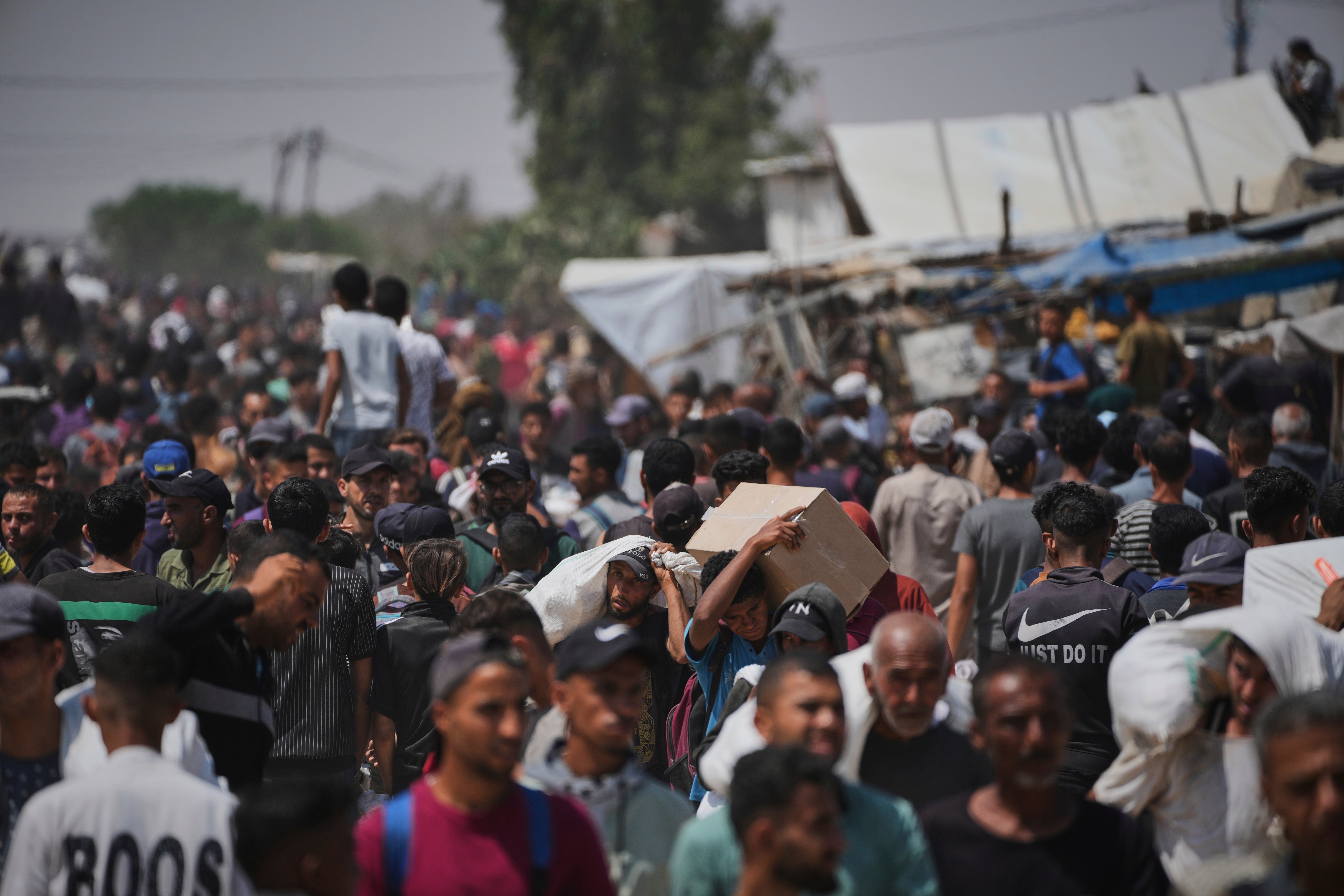 Palestinci nose kutije i torbe koje sadrže pakete za hranu i humanitarne pomoći koje isporučuje GHF u RAFAH