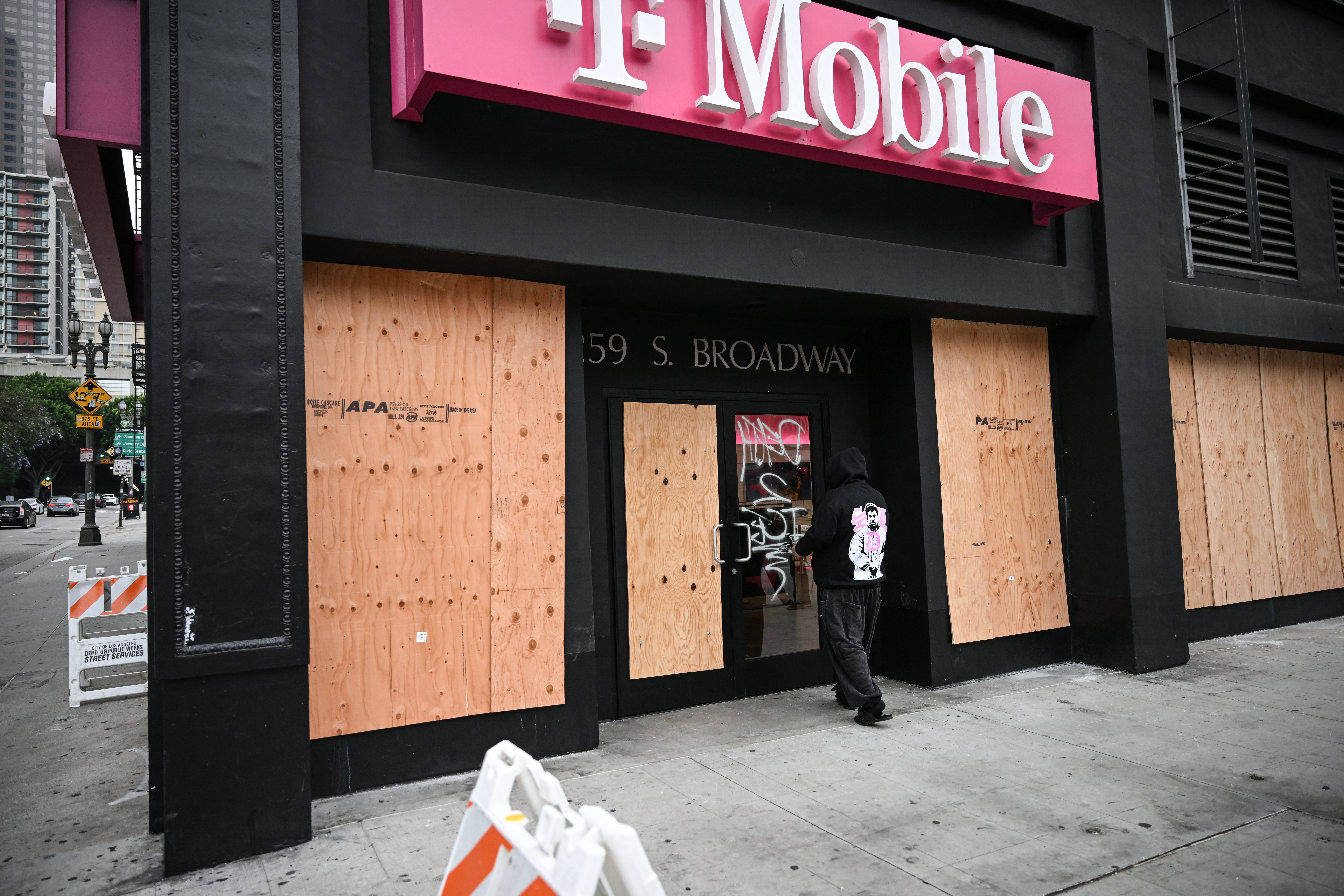 Čovjek prolazi pokraj ukrcane trgovine T-Mobile koja je u nedjelju bila opljačkana preko noći