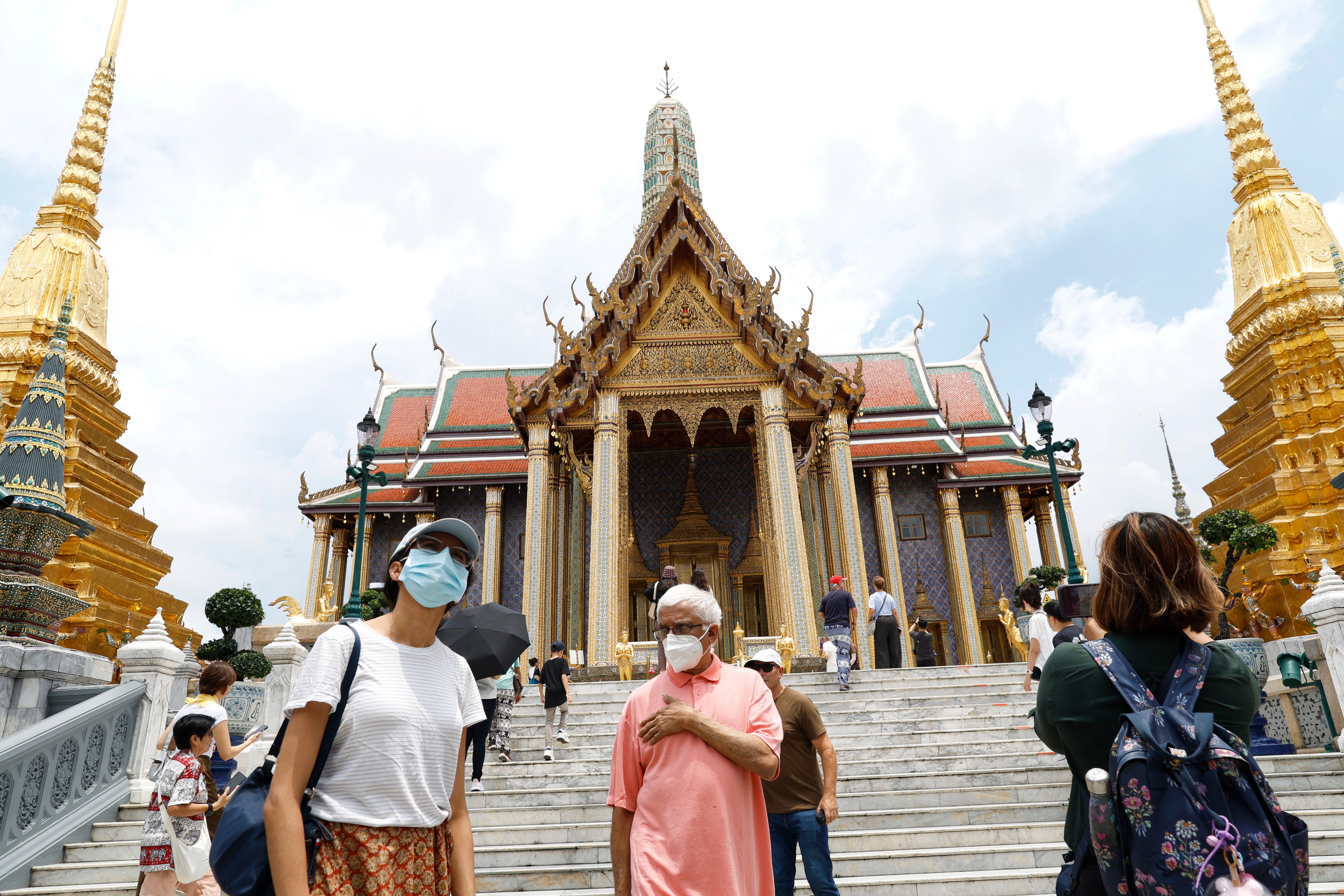 Ljudi nose maske za lice u hramu smaragdne Bude u Bangkoku na Tajlandu