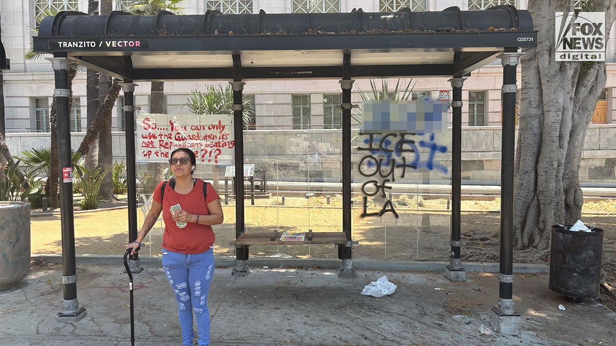 Žena stoji ispred grafitiranog autobusnog stajališta u centru Los Angelesa