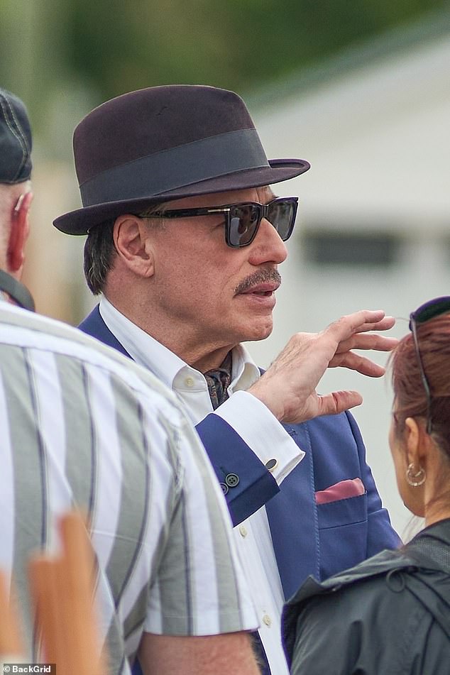 Odjeven u oštro mornaričko odijelo s maroon fedorom i retro nijansama, u potpunosti je utjelovio mafijaša Johnnyja Rosellija, ključnog igrača u glasinama CIA -e za ubojstvo Castroa