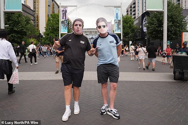 Navijači Oasisa koji nose Liam i Noel Gallagher maske poziraju za fotografiju izvan stadiona, uoči prve večeri Oasis Live '25 turneje na Wembley stadionu u Londonu