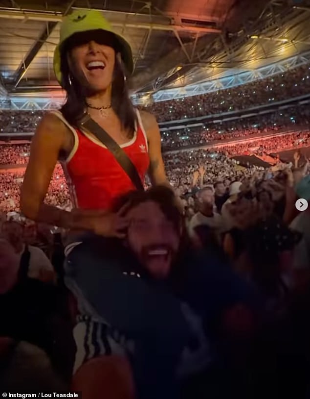 Lou je kliznula u crveni Adidas Crop Top dok se smjestila na Andyjevim ramenima kako bi gledala emisiju uživo