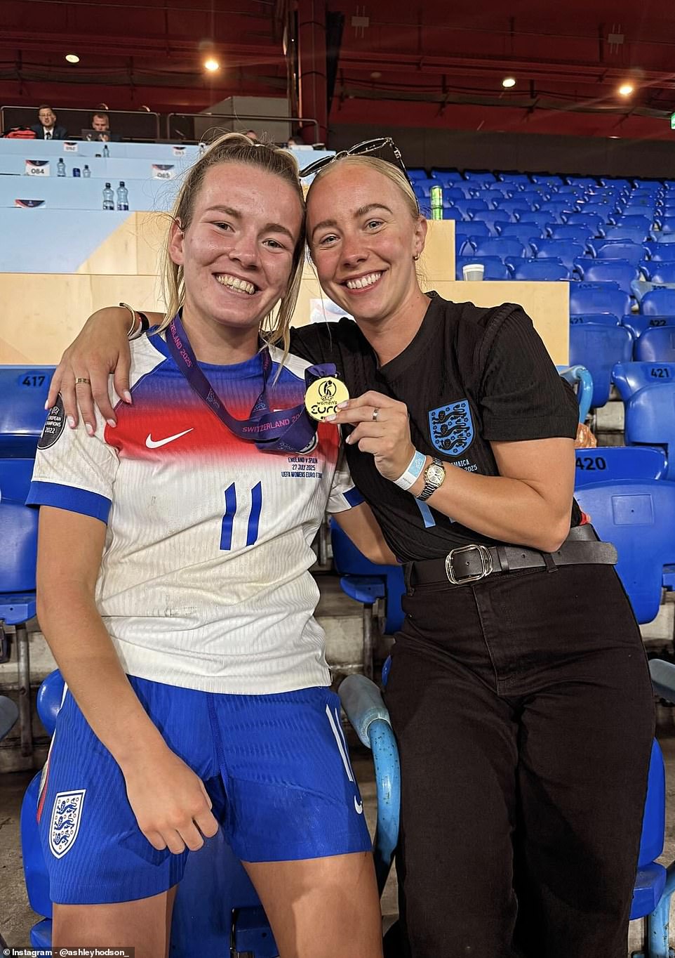 No 11 Lauren konoplja se široko nasmiješila dok je pozirala pored djevojke Ashley Hodson na tribinama