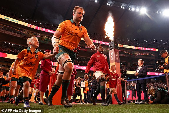 Australia's captain Harry Wilson (L) and British and Irish Lions captian Maro Itoje lead their teams out onto the field at the start of the second rugby Test match at the Melbourne Cricket Ground (MCG) on July 26, 2025. (Photo by Martin KEEP / AFP) / -- IMAGE RESTRICTED TO EDITORIAL USE - STRICTLY NO COMMERCIAL USE  (Photo by MARTIN KEEP/AFP via Getty Images)