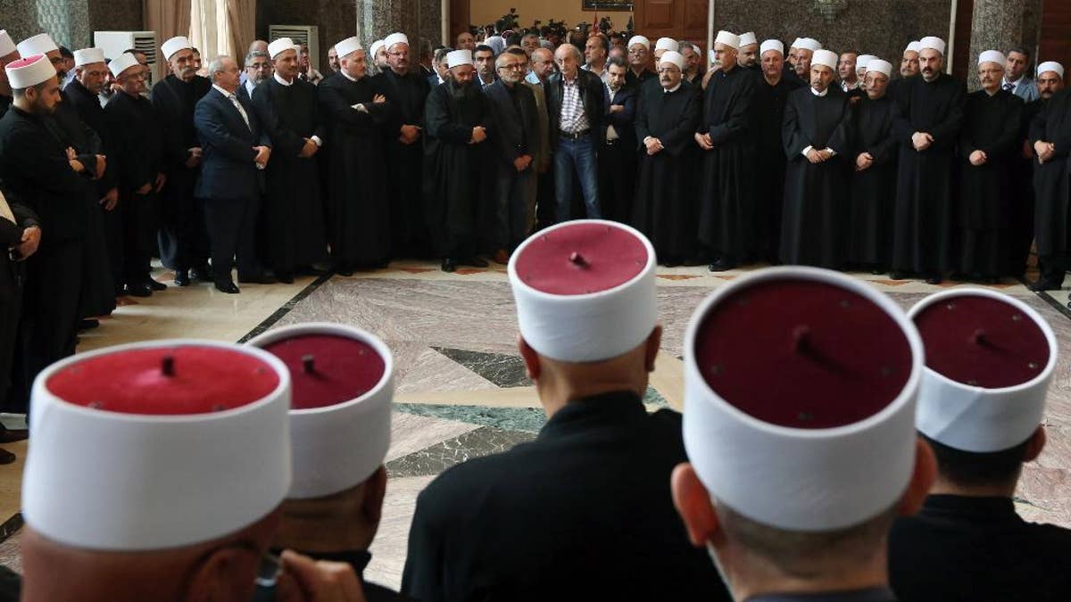 Walid Jumblatt, politički vođa libanonske sekte manjine Druze, središnja pozadina, stoji s svećenike ubrzo nakon sastanka vjerskog vodstva zajednice Druze u Beirutu, Libanon, u petak, 12. lipnja 2015.. Politički lider u libanonu, individual je to bio napad na sjeverozapadu. (AP Photo/Bilal Hussein)