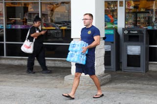 Čovjek nosi flaširanu vodu iz trgovine prehrambenim proizvodima nakon što su vlasti upozorile stanovnike na mogućnost destruktivnih valova cunamija u Honoluluu na Havajima