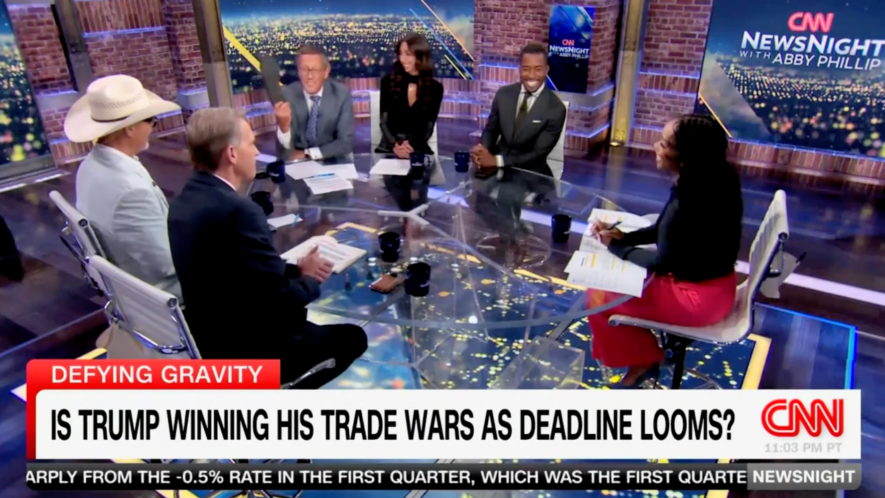CNN međunarodni poslovni dopisnik Richard Quest maše cipelom u zraku dok njegovi kolege panelisti gledaju. Quest je skinuo cipelu tijekom travnja CNN ploče, navodeći je kao primjer proizvoda koji će se povećati pod Trumpovim tarifama