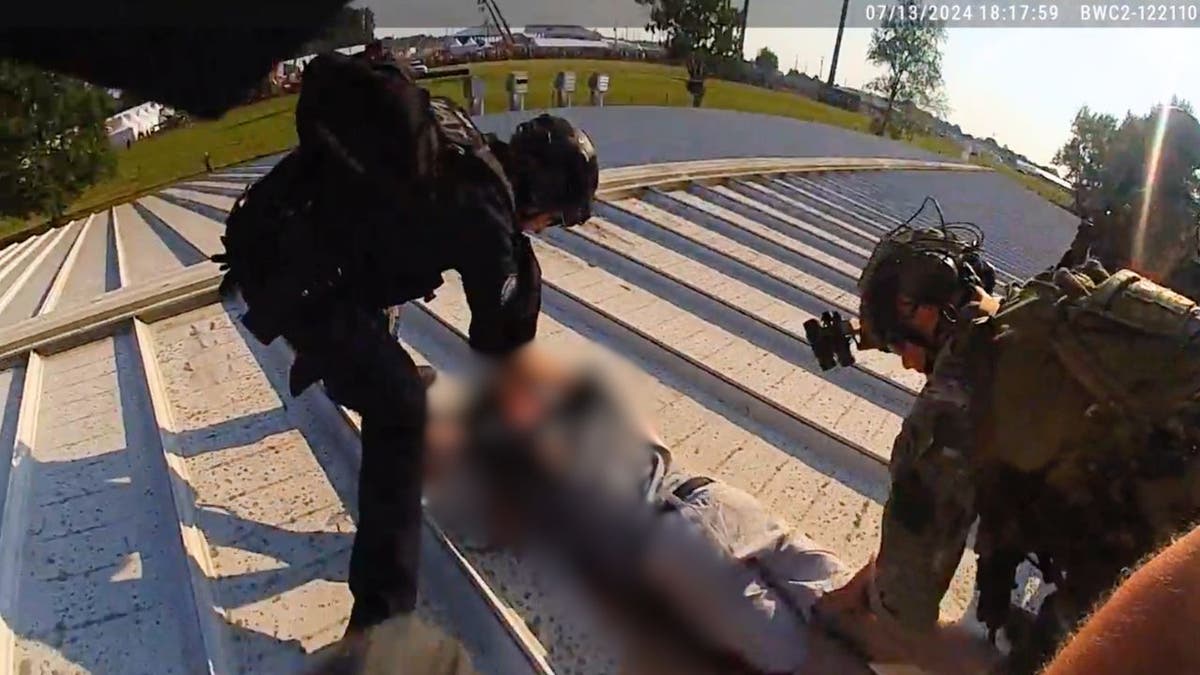 Policajci stoje nad Thomasom Crooks -om na krovu zgrade AGR