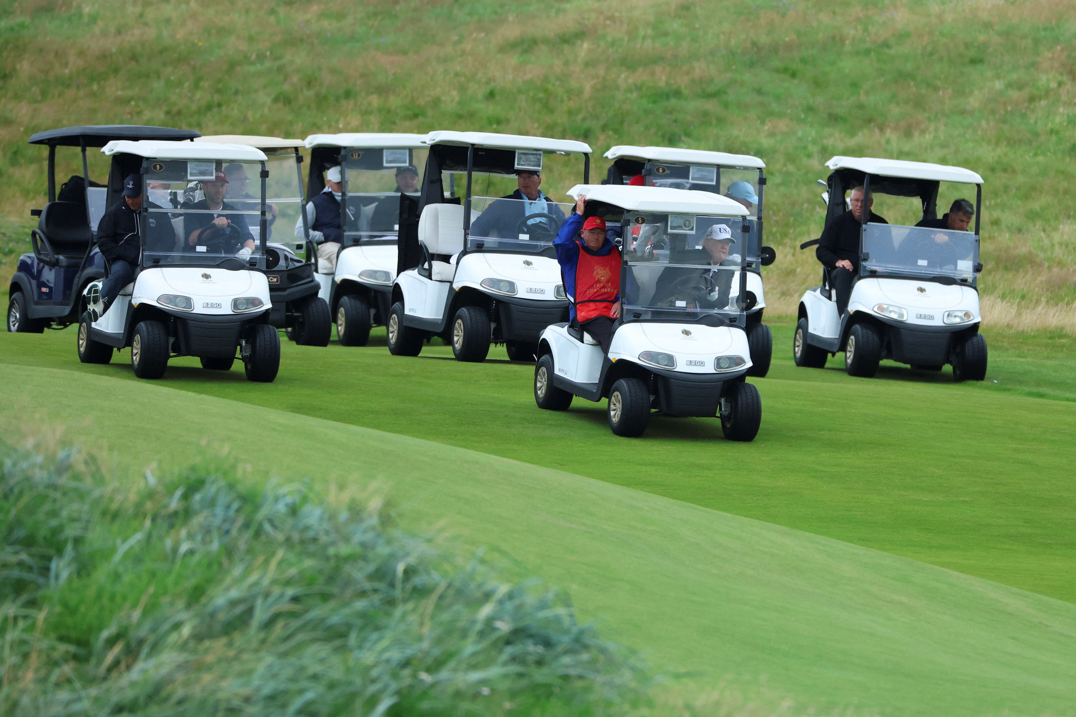 Noseći bijelu bejzbolsku kapu Brand USA, američki predsjednik mahnuo je novinarima dok je stigao u svoje golf odmaralište u bijelom golf buggy