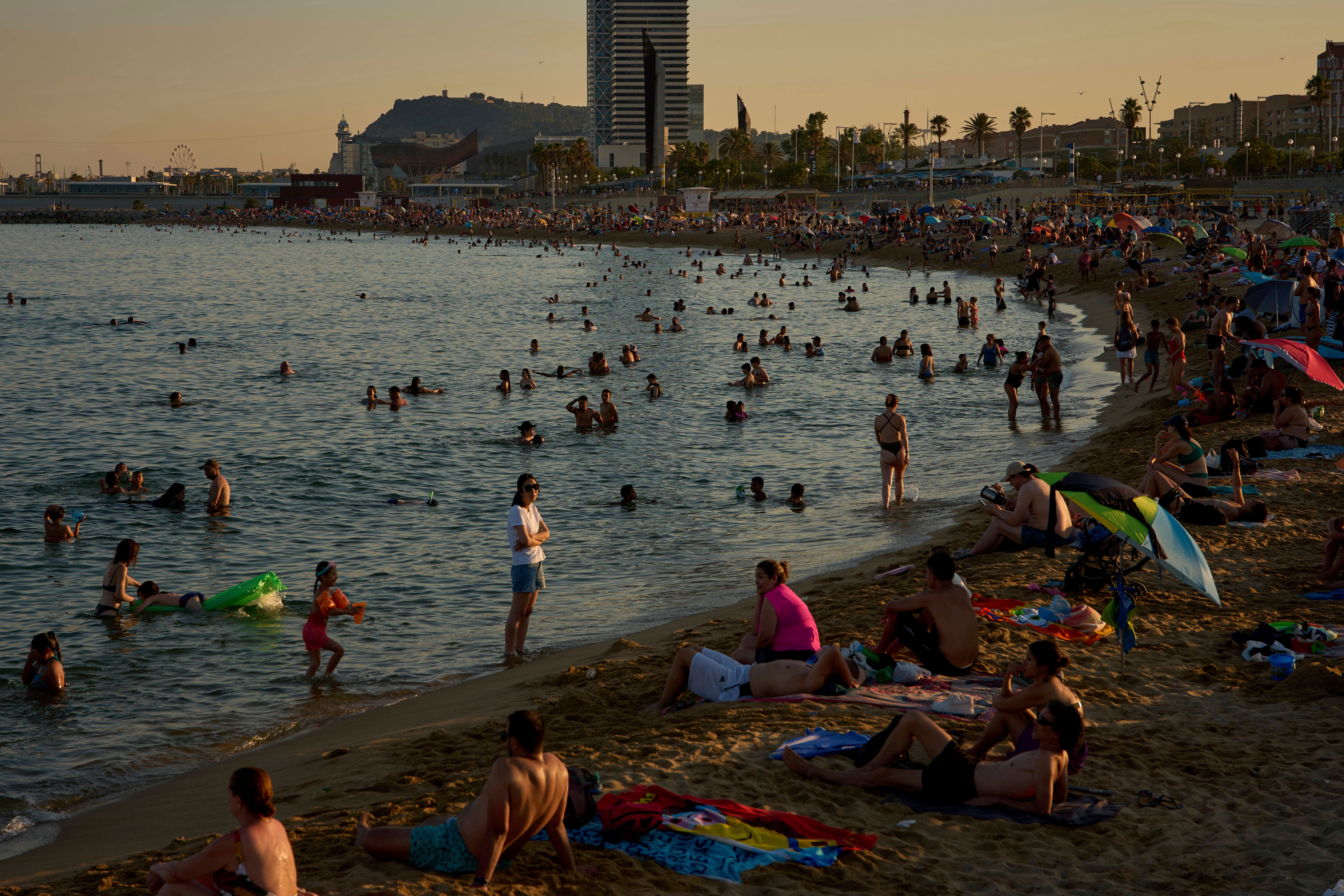Plivači se hlade u vodi na plaži vrućeg dana u Barceloni