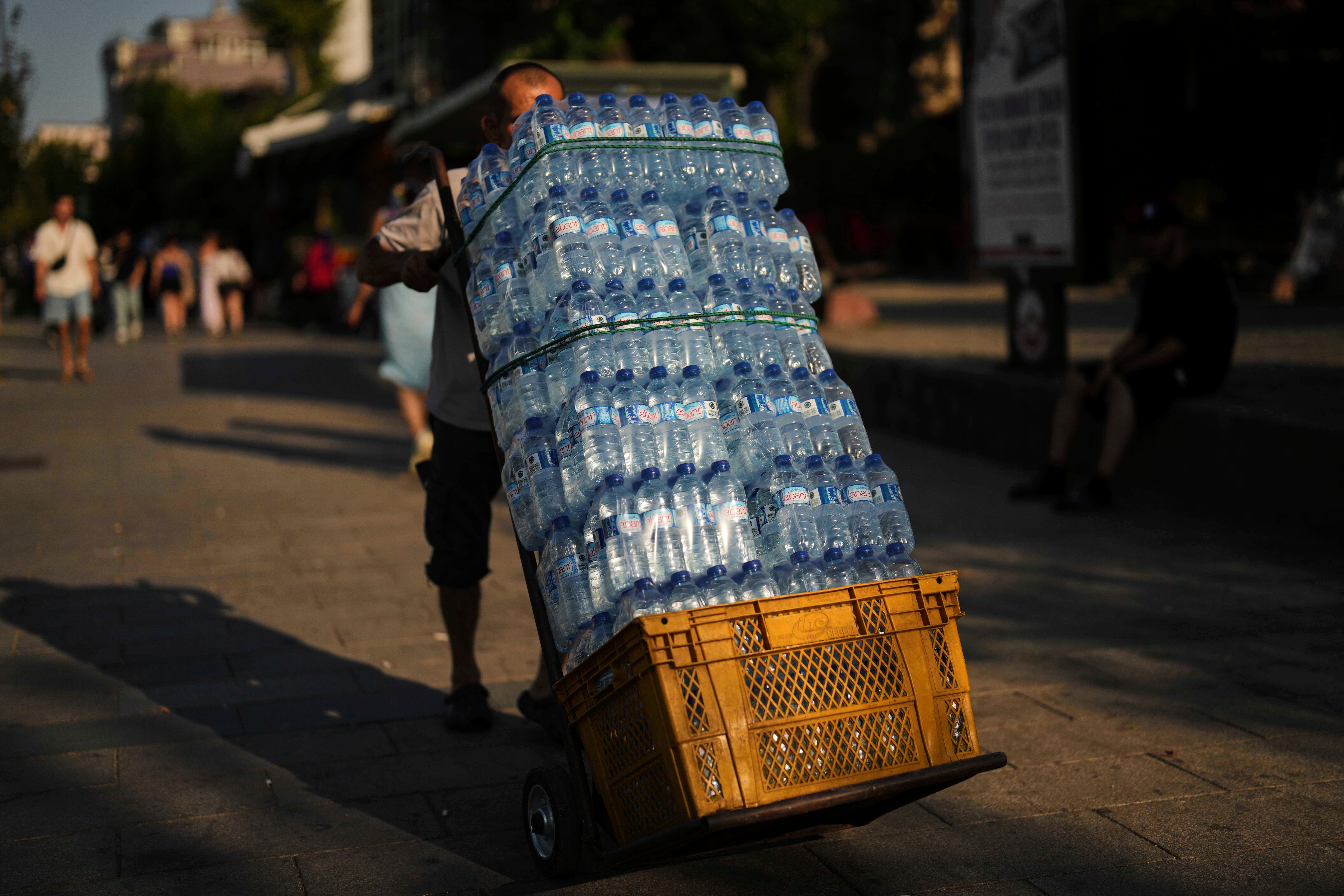 Muškarac isporučuje plastične boce vode u popularni restoran vrućeg ljetnog dana, u Istanbulu, Turska, četvrtak, 24. srpnja 2025. (AP Photo/Francisco Seco)