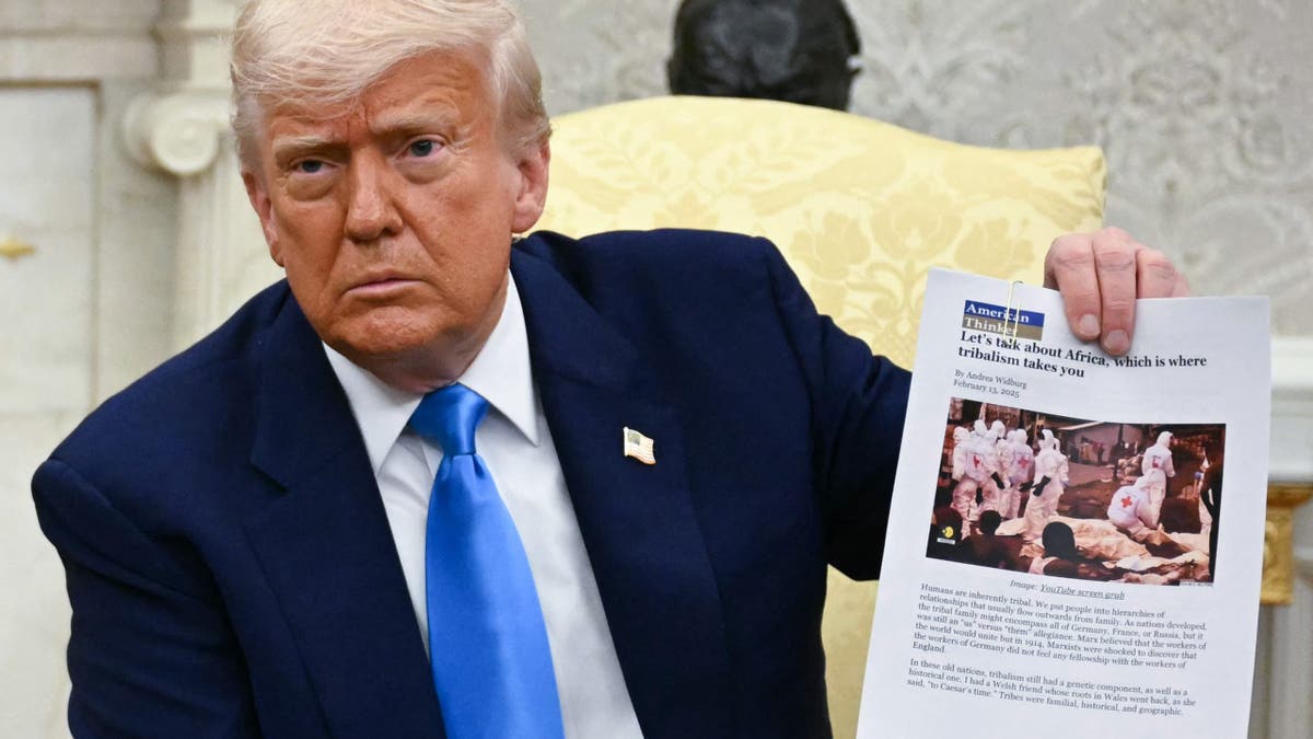 Predsjednik Donald Trump drži isječak novina u Ovalnom uredu