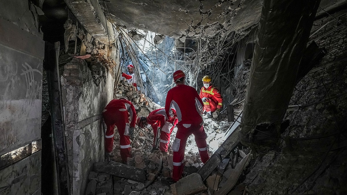 Spasioci u crvenim odijelima koji pretražuju ruševine