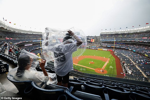 Obožavatelj koji nosi Aaronovog suca Jerseyja kako povuče pončo dok kiša počinje padati
