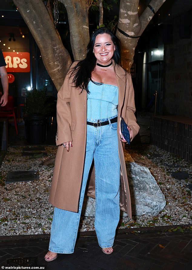 Ashleigh Ackerman držao je stvari bez napora u glatkim traper hlačama i odgovarajućim vrhom, slojevitim sa stilskim preplanulim kaputom